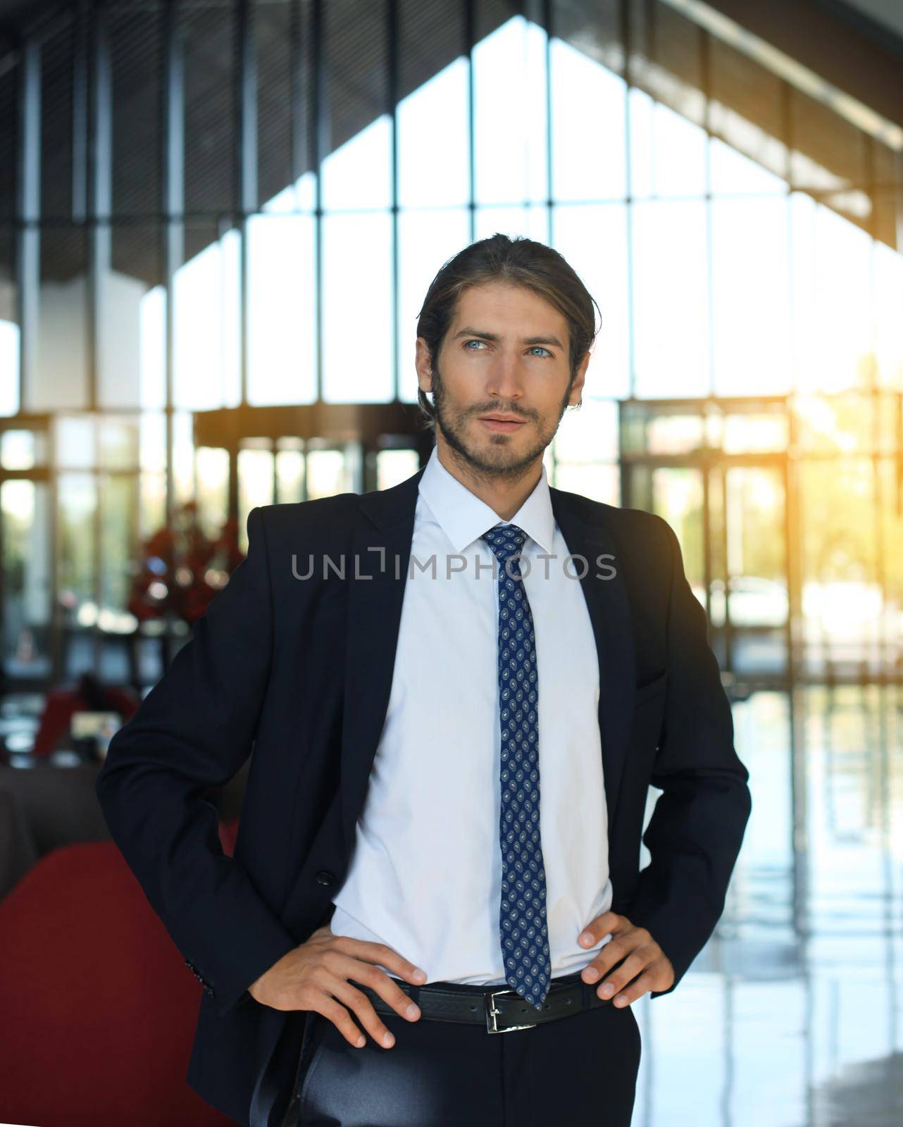 Portrait of happy young businessman standing in hotel lobby. by tsyhun