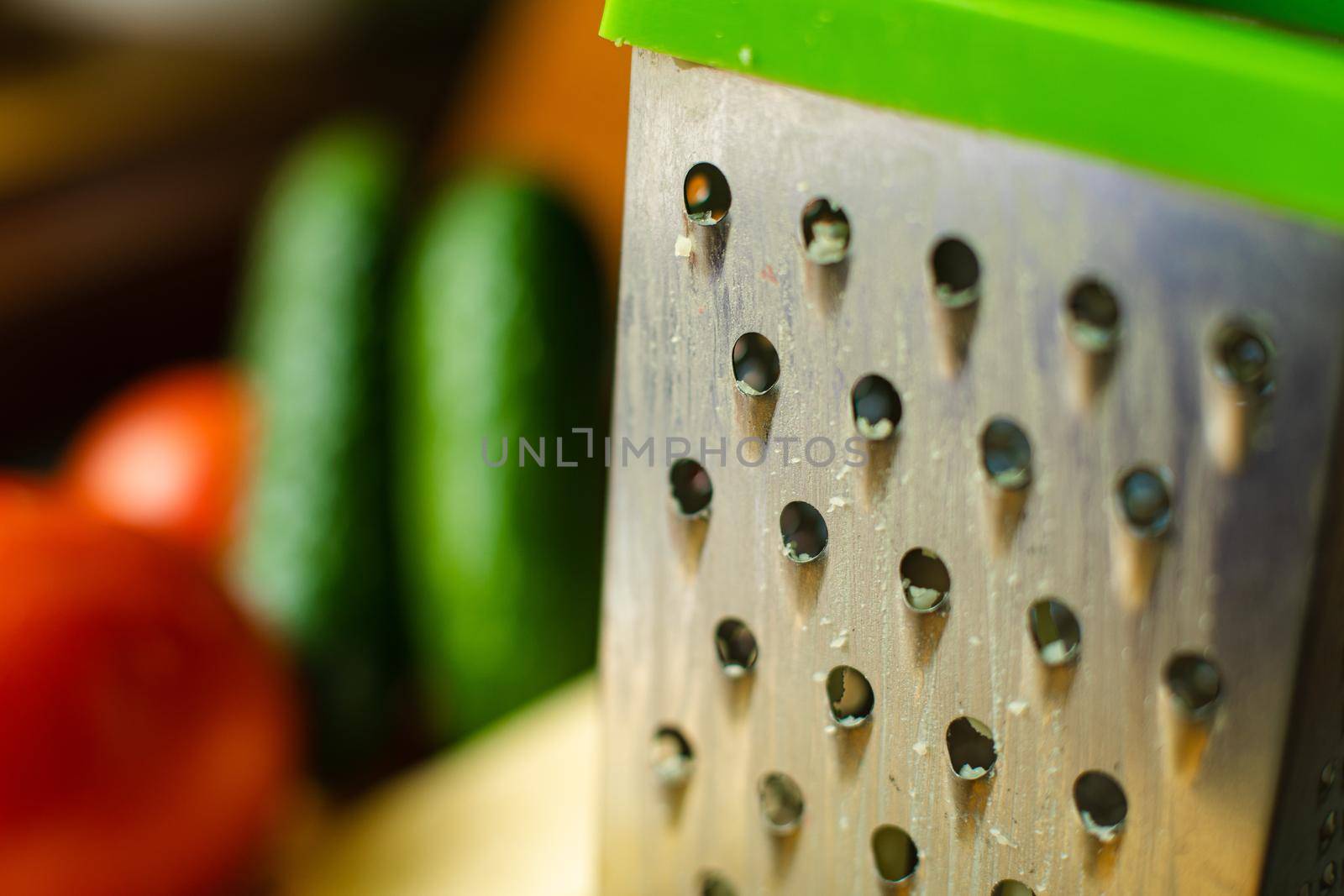 Picture of metal kitchen grater with oval holes on it on the kitchen table by StudioLucky