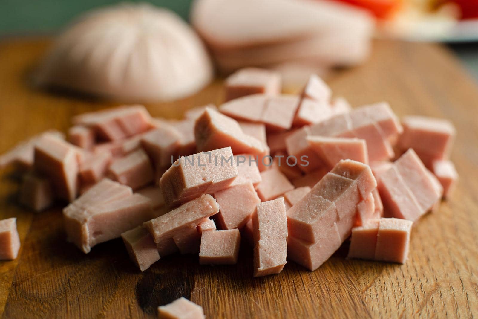 Picture of a small pile of cube sliced sausage for cooking on a wooden table in the kitchen