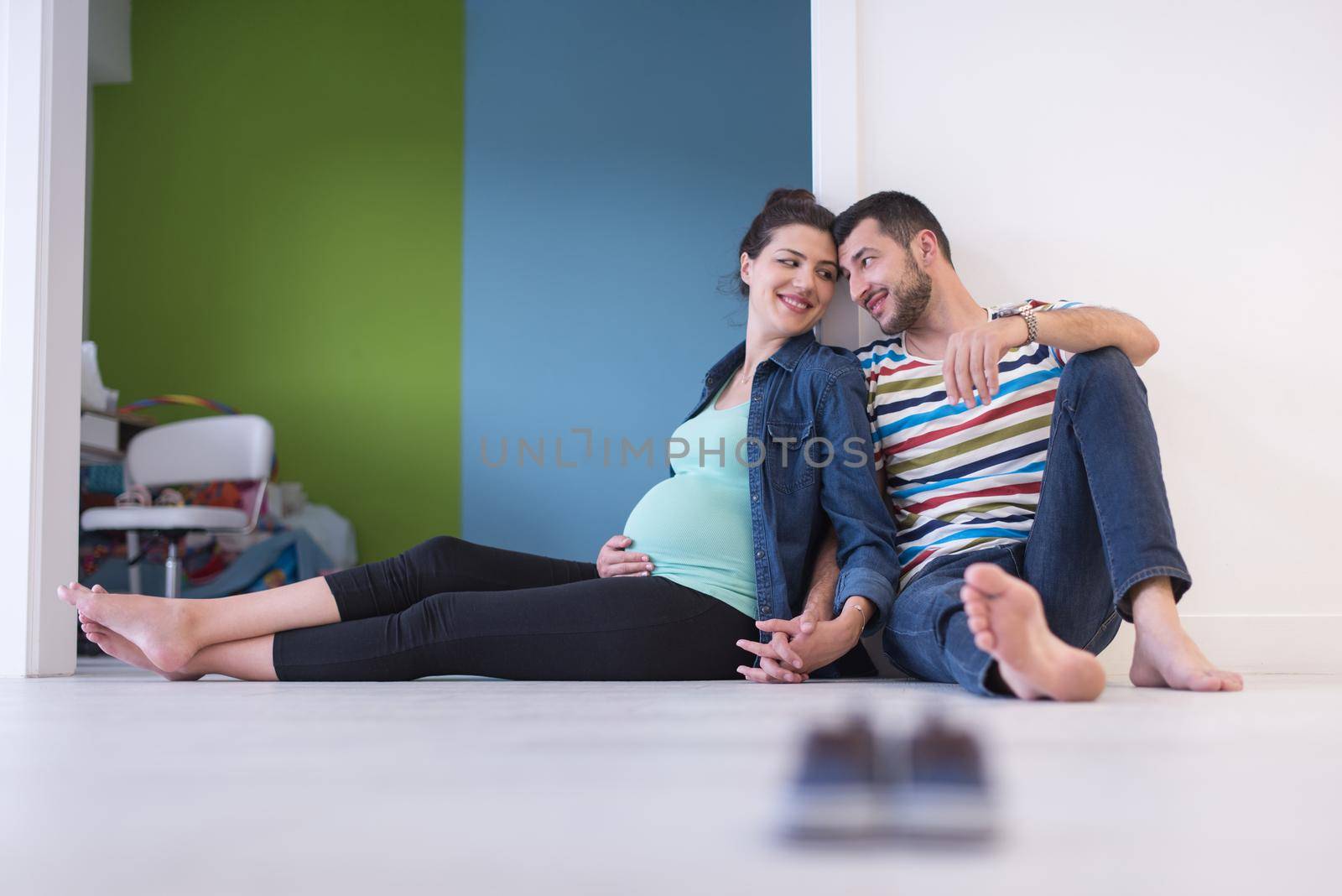 happy pregnant couple holding their hands while sitting on the floor at home
