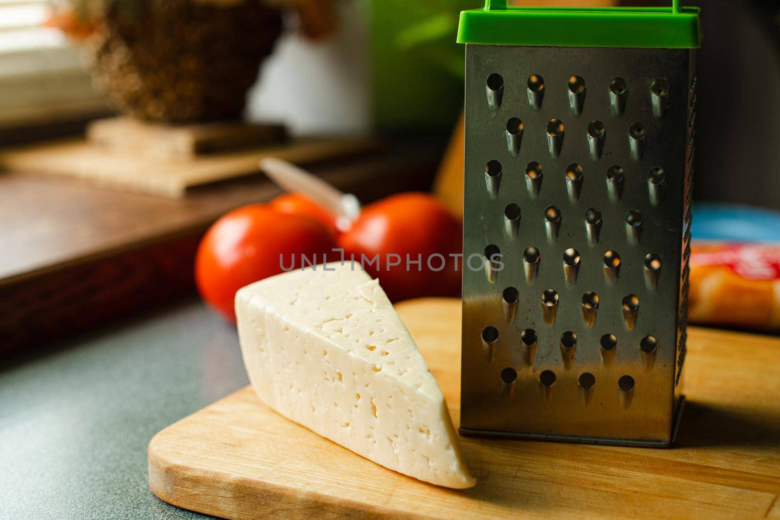 Picture of metal kitchen grater with oval holes on it on the kitchen table by StudioLucky