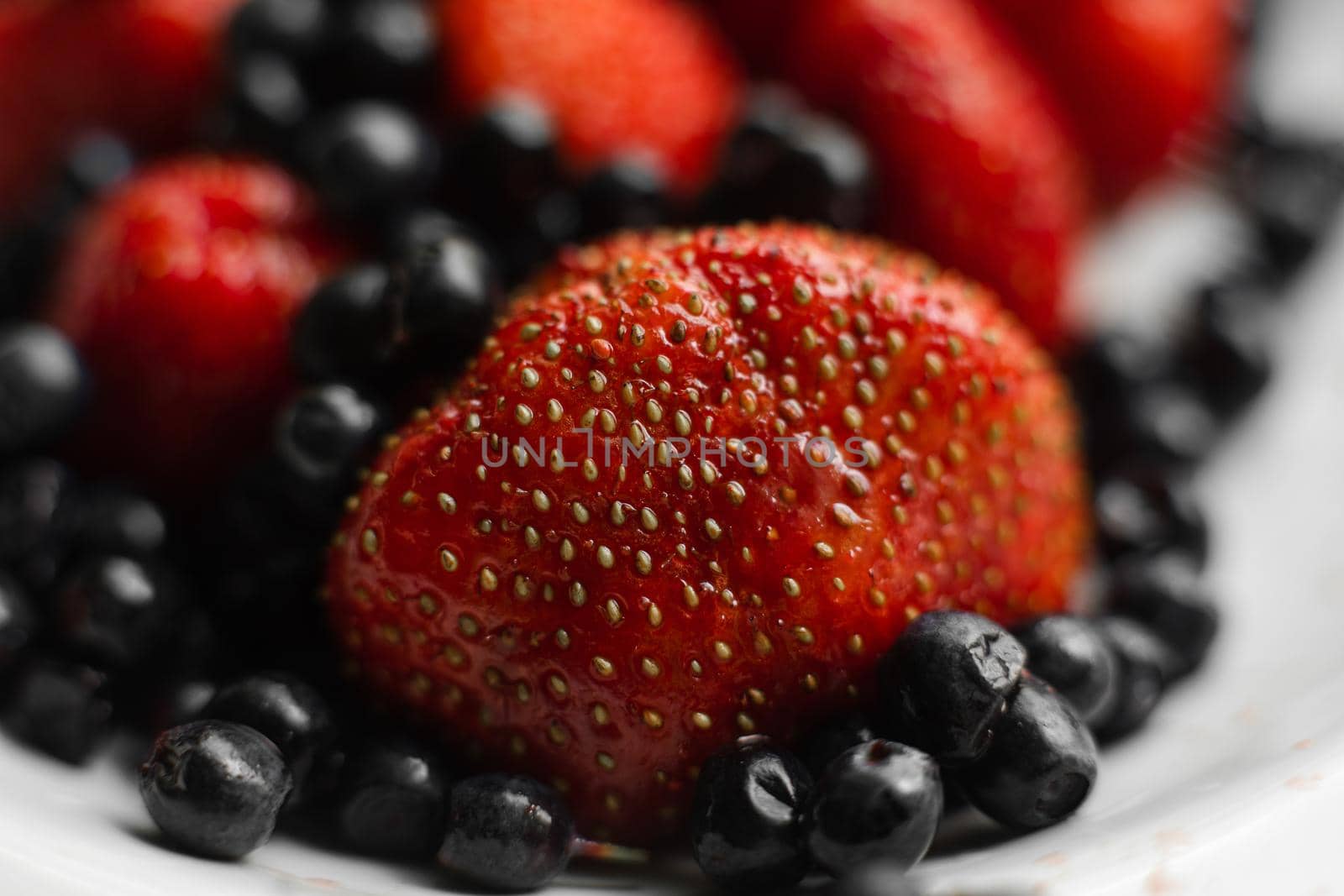 Many juicy fresh ripe red strawberry berries with blackberries isolated on white background by StudioLucky