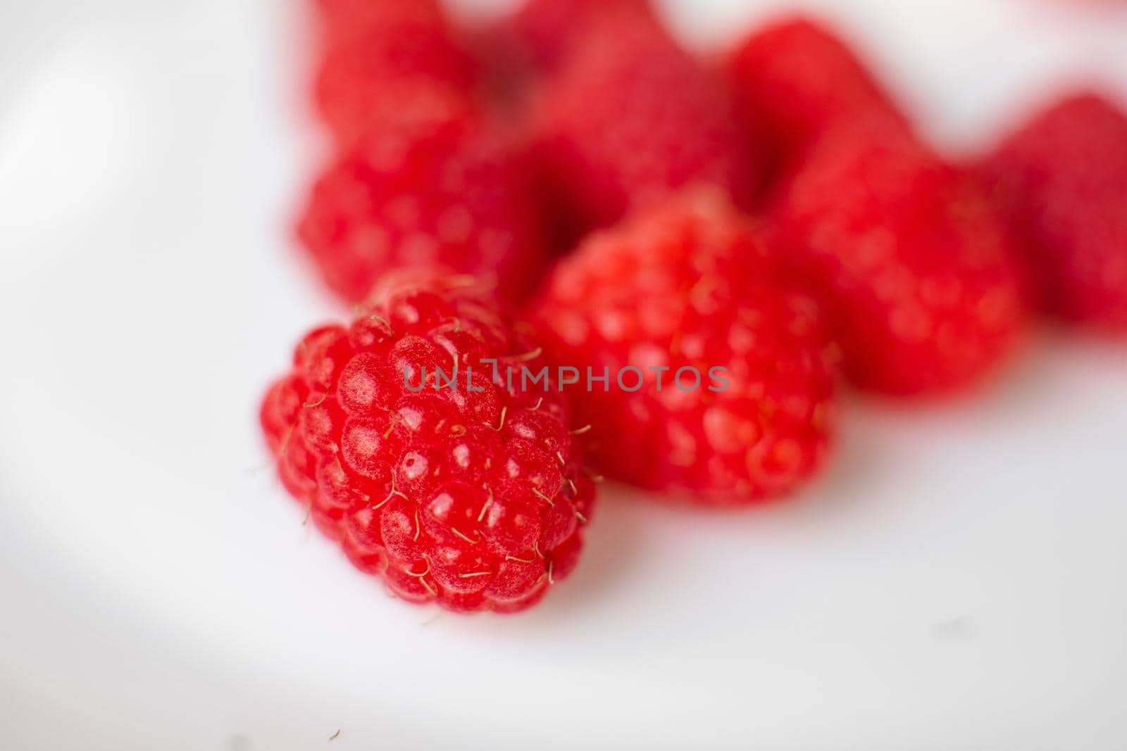 A picture of a few fresh pink raspberries lies on a white background. Background and picture for postcard.