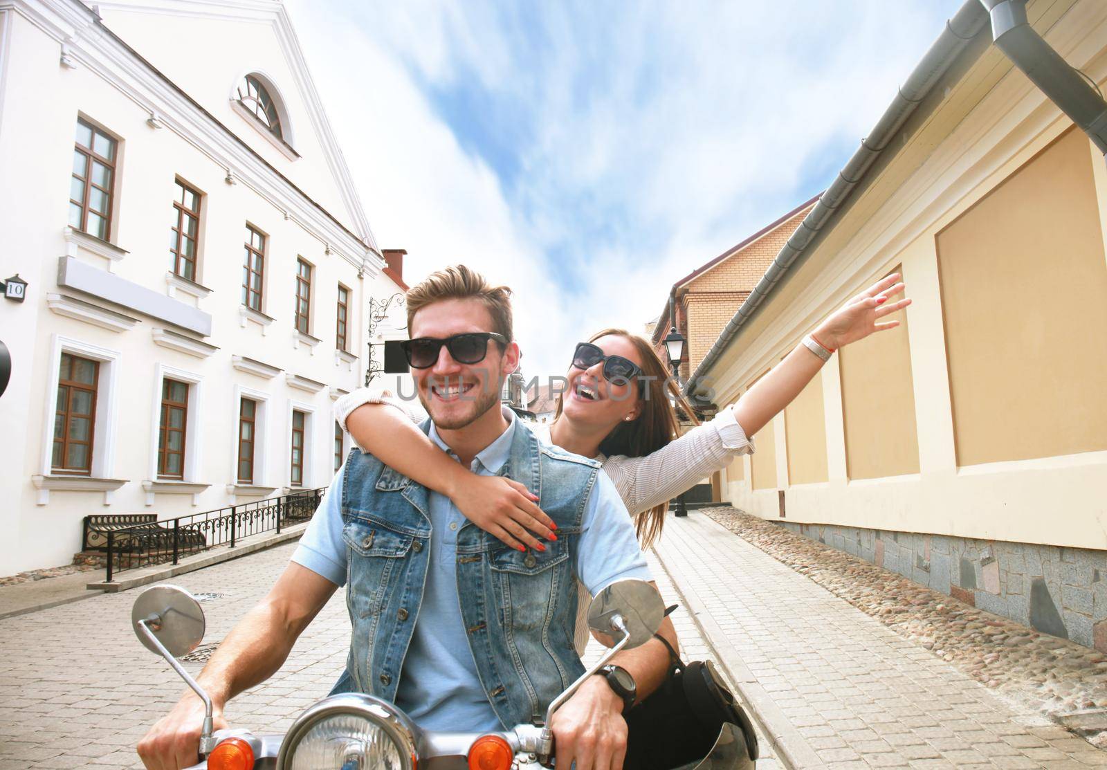 happy young couple riding scooter in town. Handsome guy and young woman travel. Adventure and vacations concept.