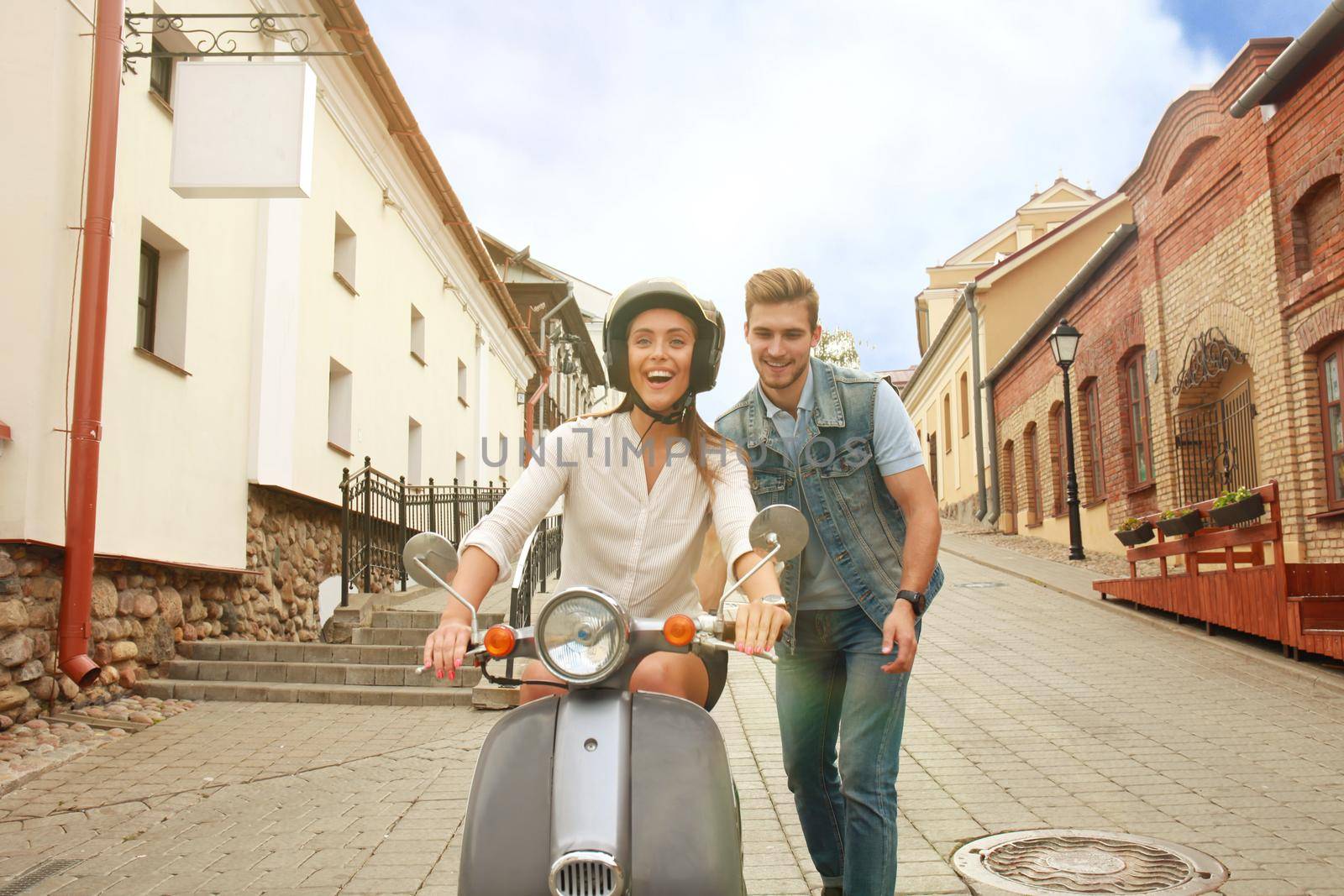 happy young couple riding scooter in town. Handsome guy and young woman travel. Adventure and vacations concept.