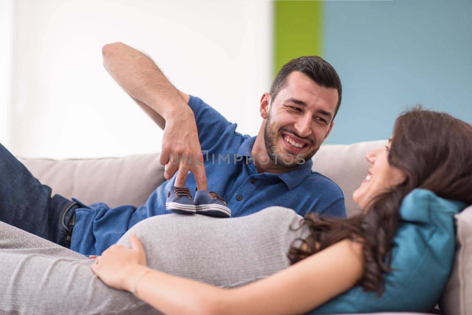 happy pregnant couple relaxing on sofa couch at home