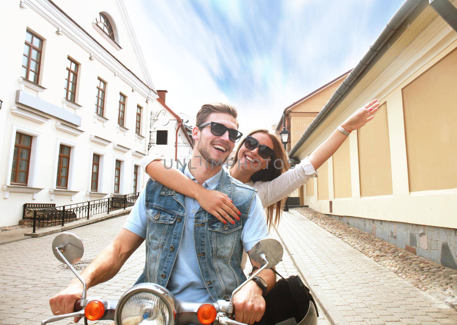 happy young couple riding scooter in town. Handsome guy and young woman travel. Adventure and vacations concept.