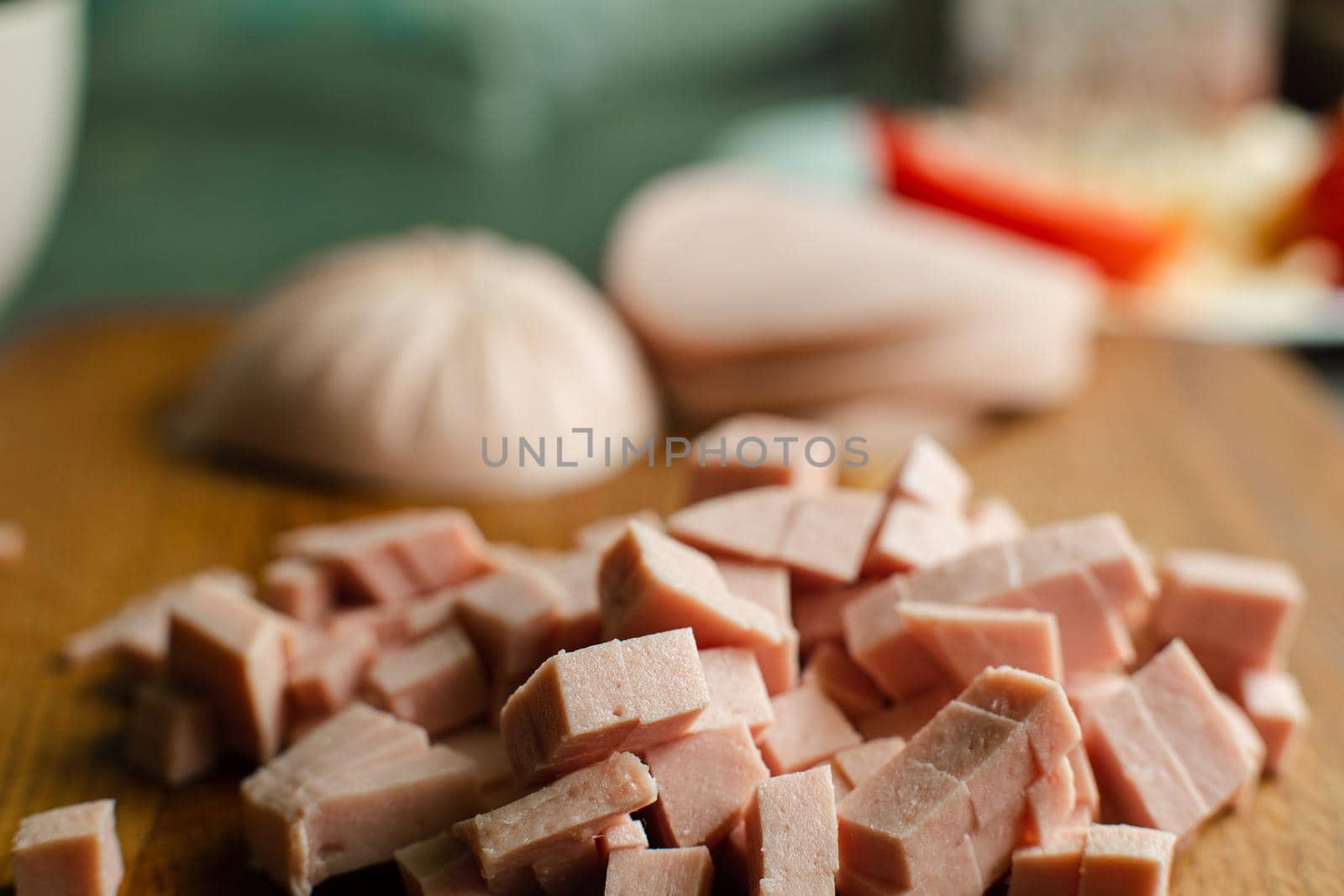 A small pile of sliced sausage for cooking on a wooden table by StudioLucky