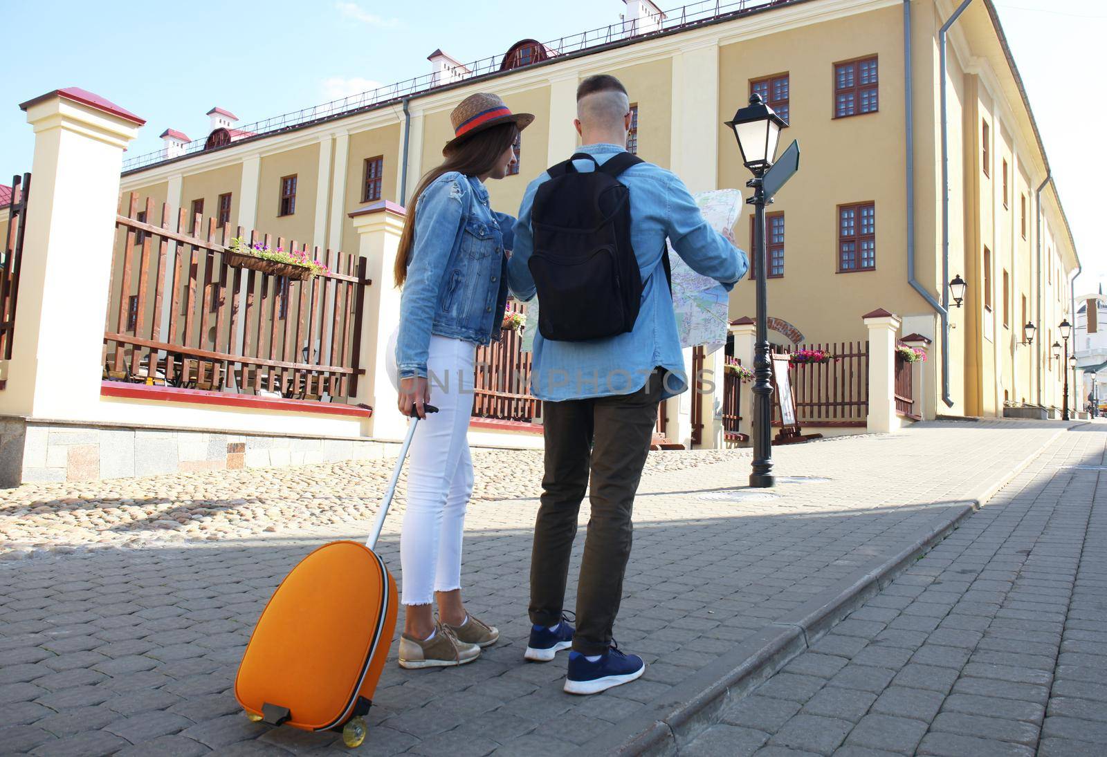 Happy couple walking outdoors sightseeing and holding a map. by tsyhun