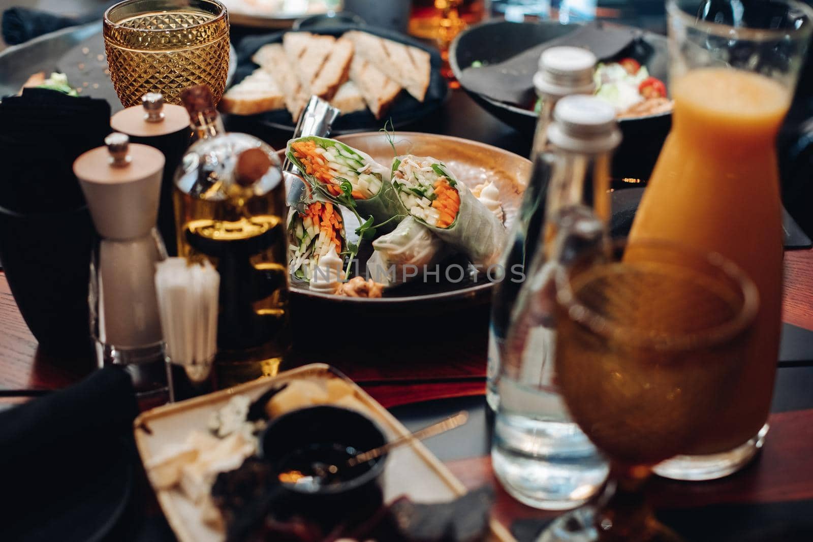 Stock photo of vegetable rolls with cucumber, carrot and greens in rice paper served on plate on table in restaurant.