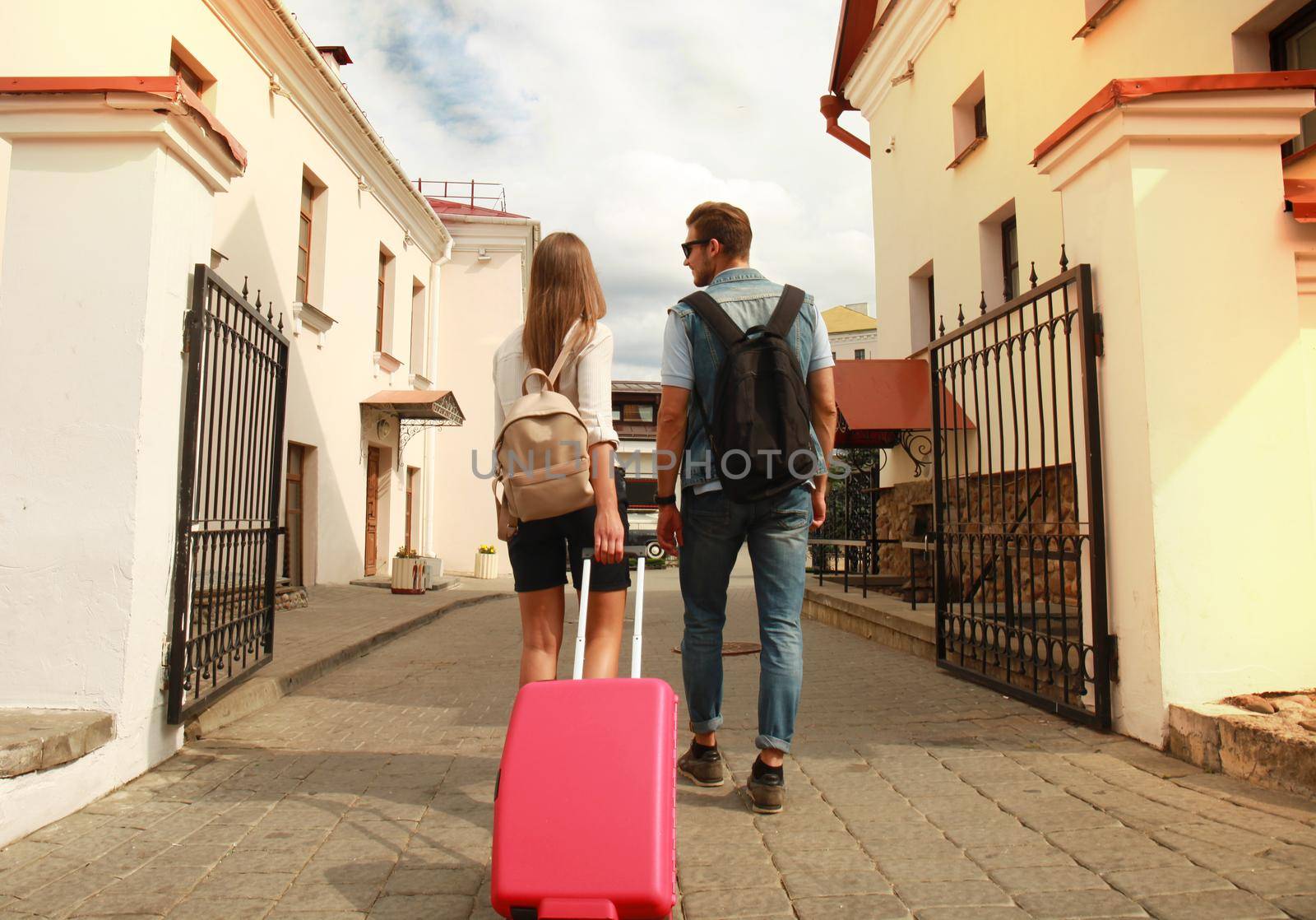 Two travelers on vacation walking around the city with luggage. by tsyhun