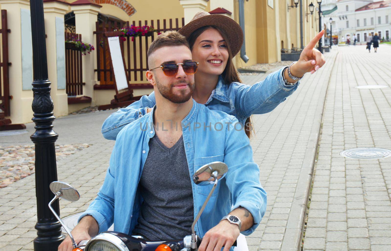 happy young couple riding scooter in town. Handsome guy and young woman travel. Adventure and vacations concept. by tsyhun