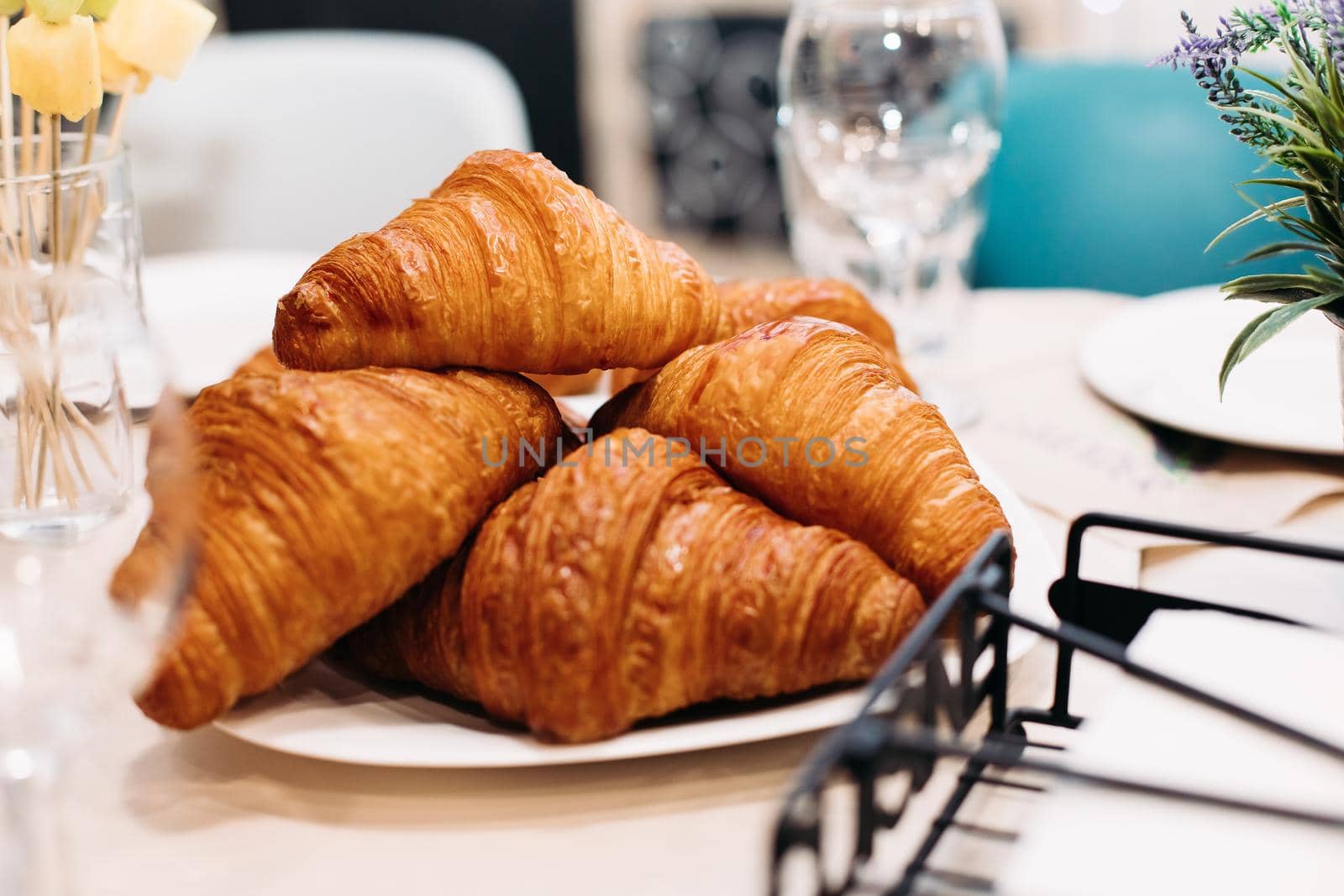 Tasty crisp croissants on a white plate sitting on table by StudioLucky