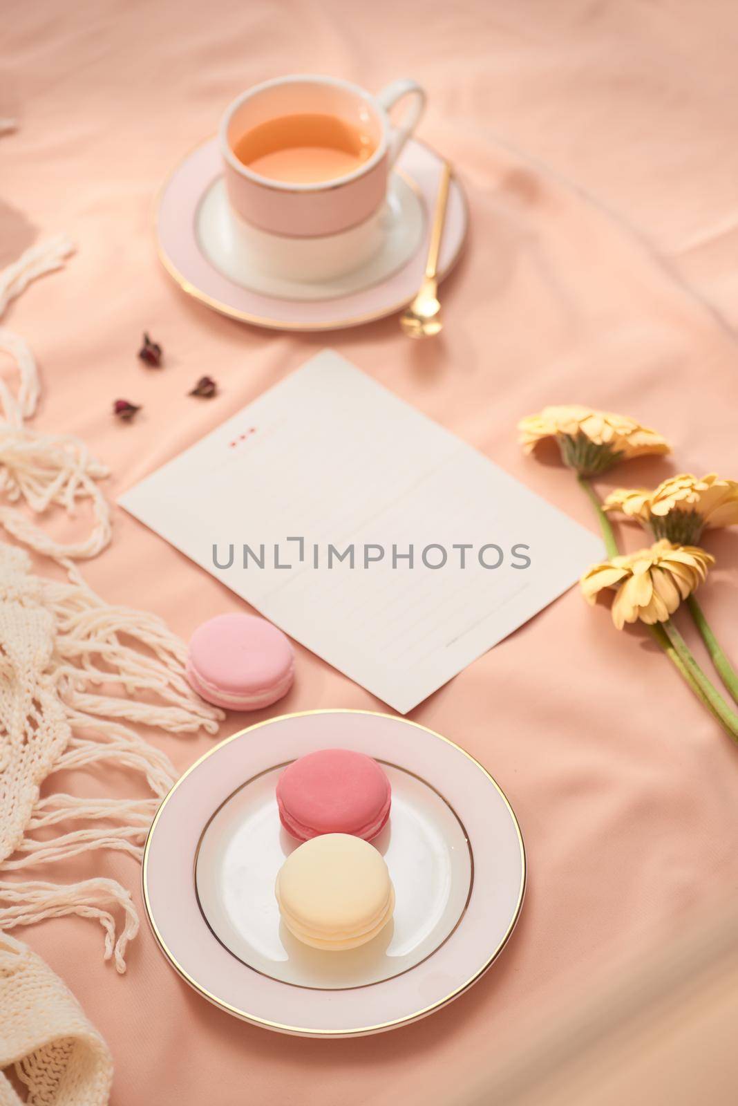 Envelope, flowers, and macarons with cup of tea on light background by makidotvn