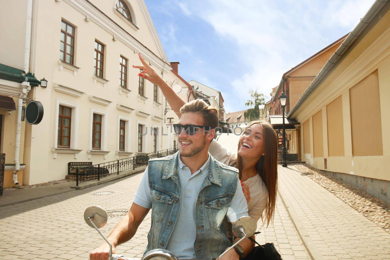 happy young couple riding scooter in town. Handsome guy and young woman travel. Adventure and vacations concept.