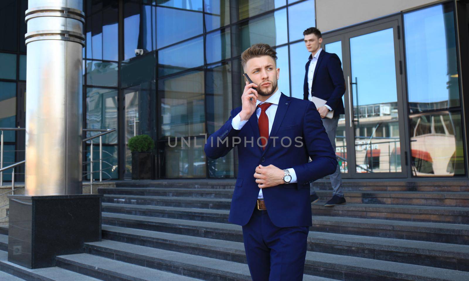 Young urban businessman professional on smartphone walking in street using mobile phone. by tsyhun