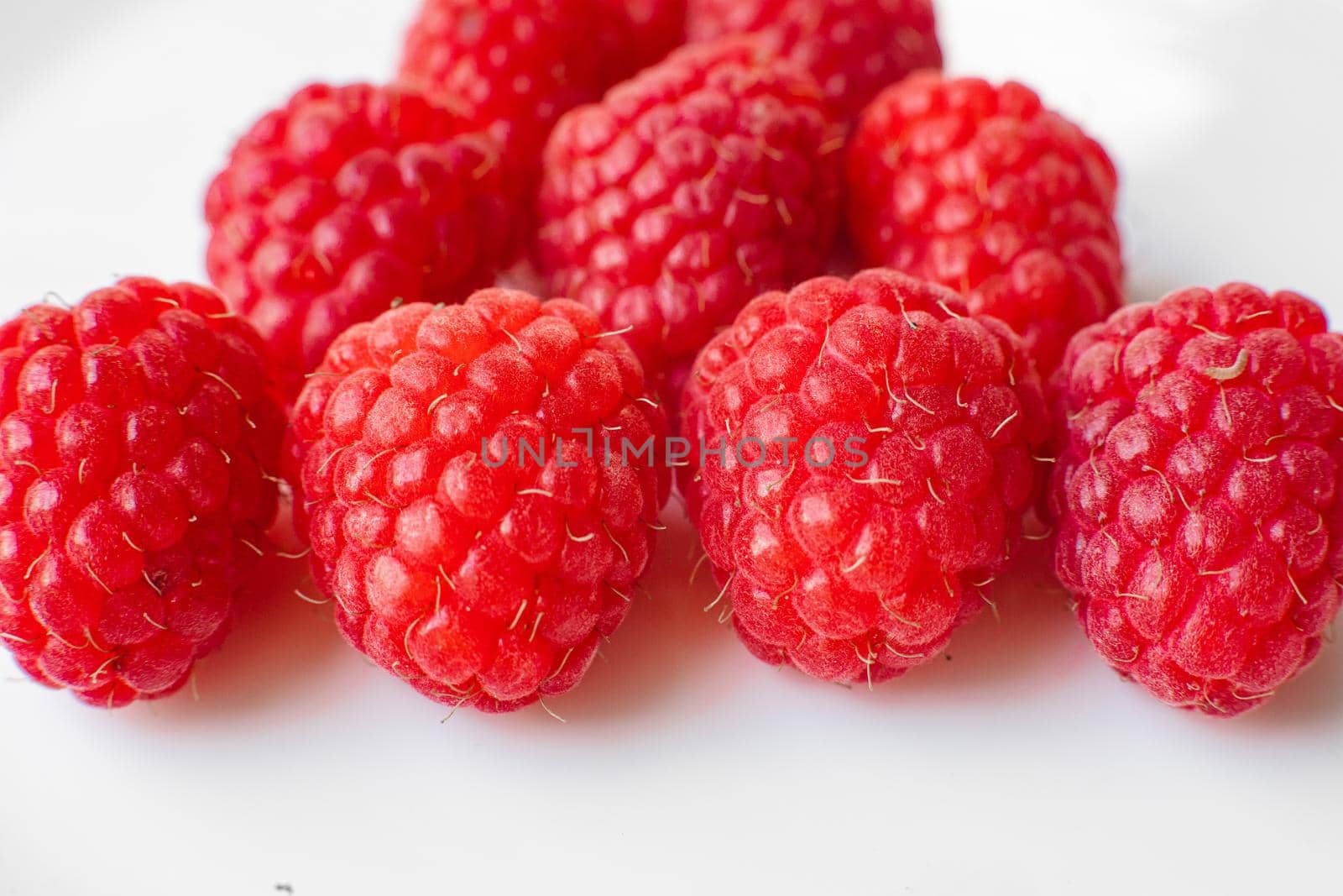 A picture of a few fresh pink raspberries lies on a white background. Background and picture for postcard.