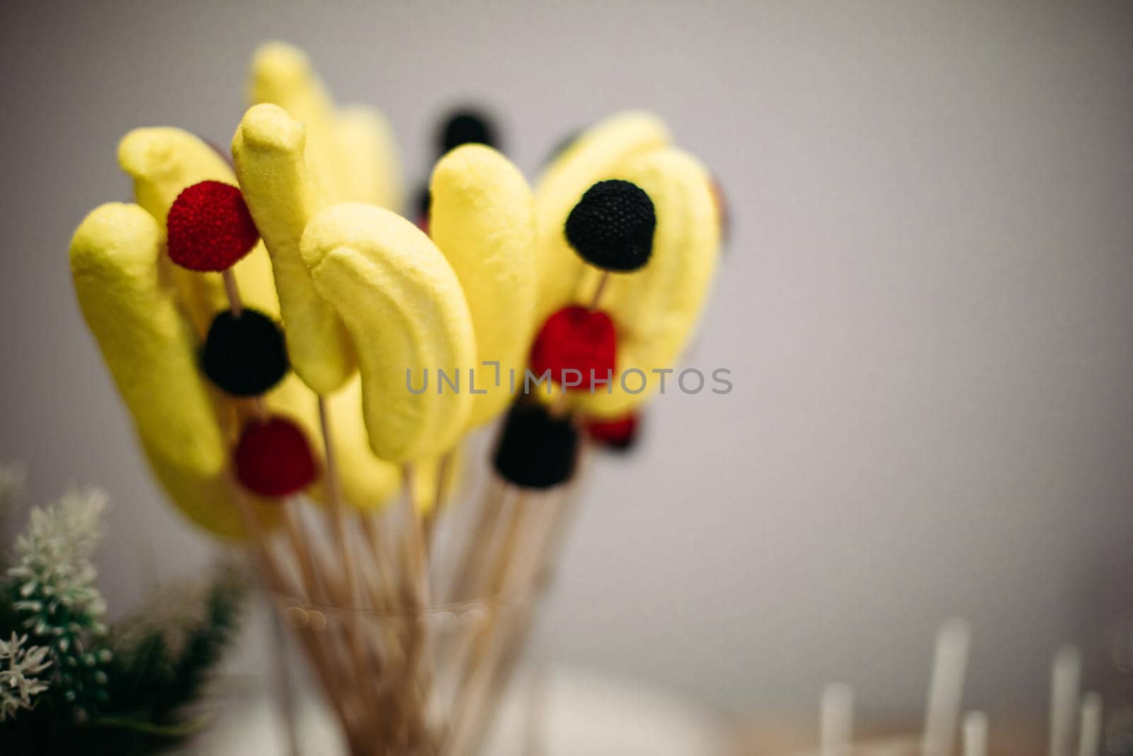 a dessert of banana and berry marshmallows on sticks in a beautiful glass jar