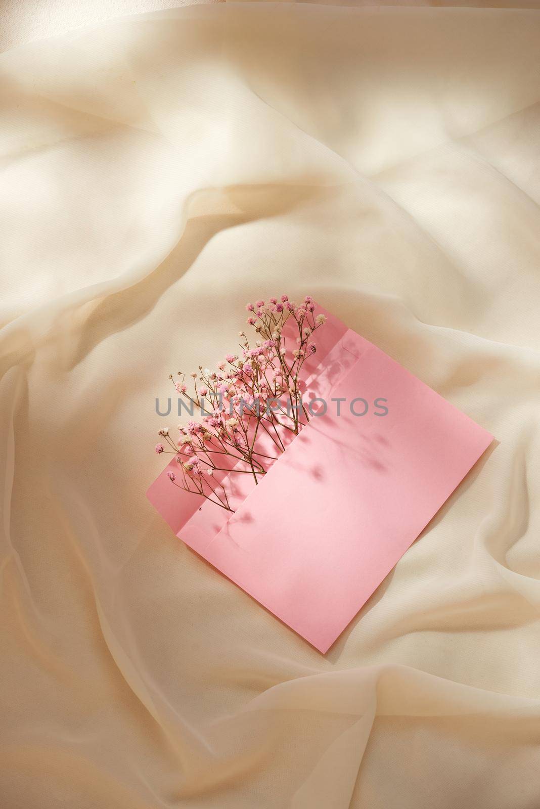 Pink envelope with a spring flower arrangement. Flat lay, top view