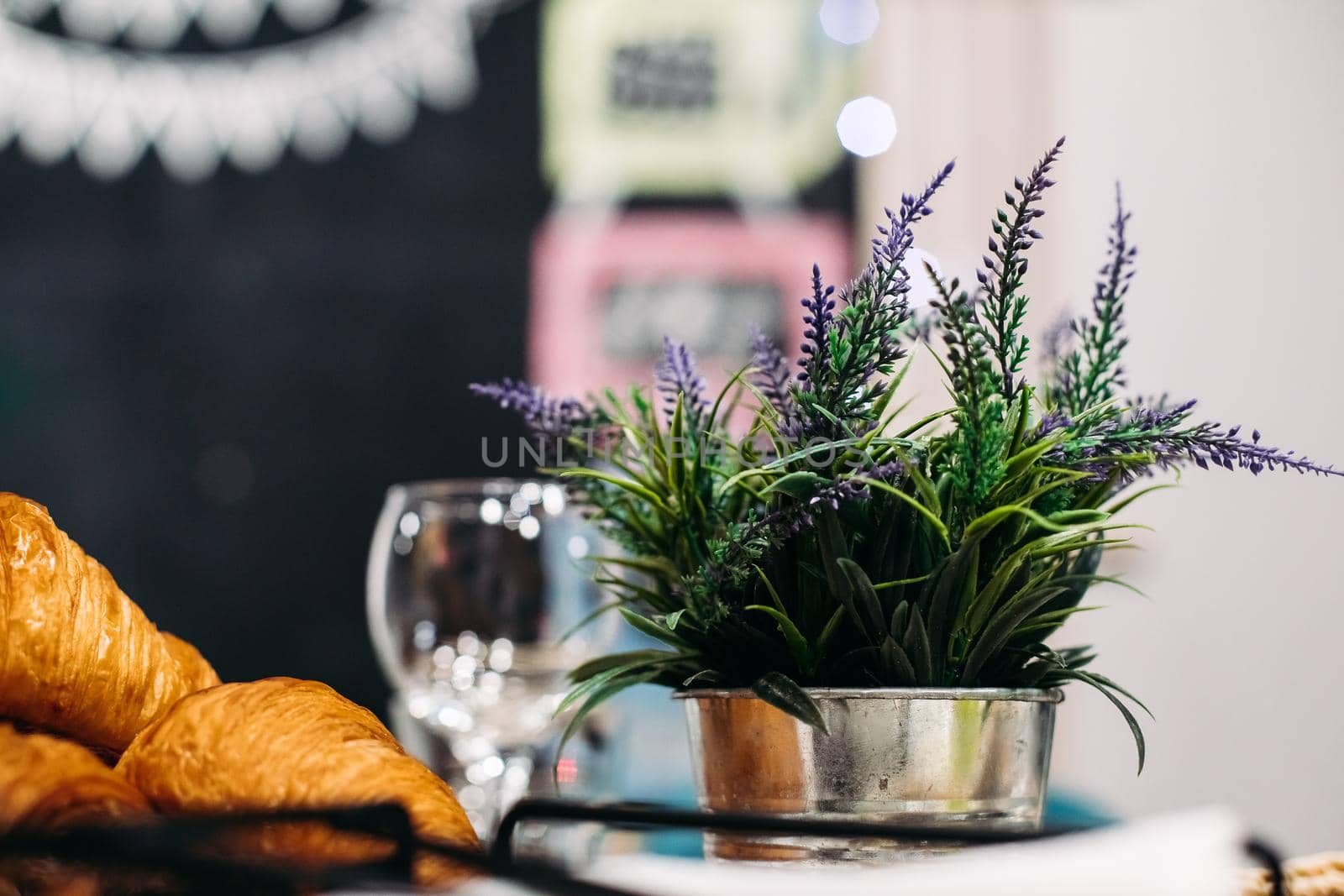 Stock photo of fresh lavender flowers in steel silver pot next to freshly baked croissants.