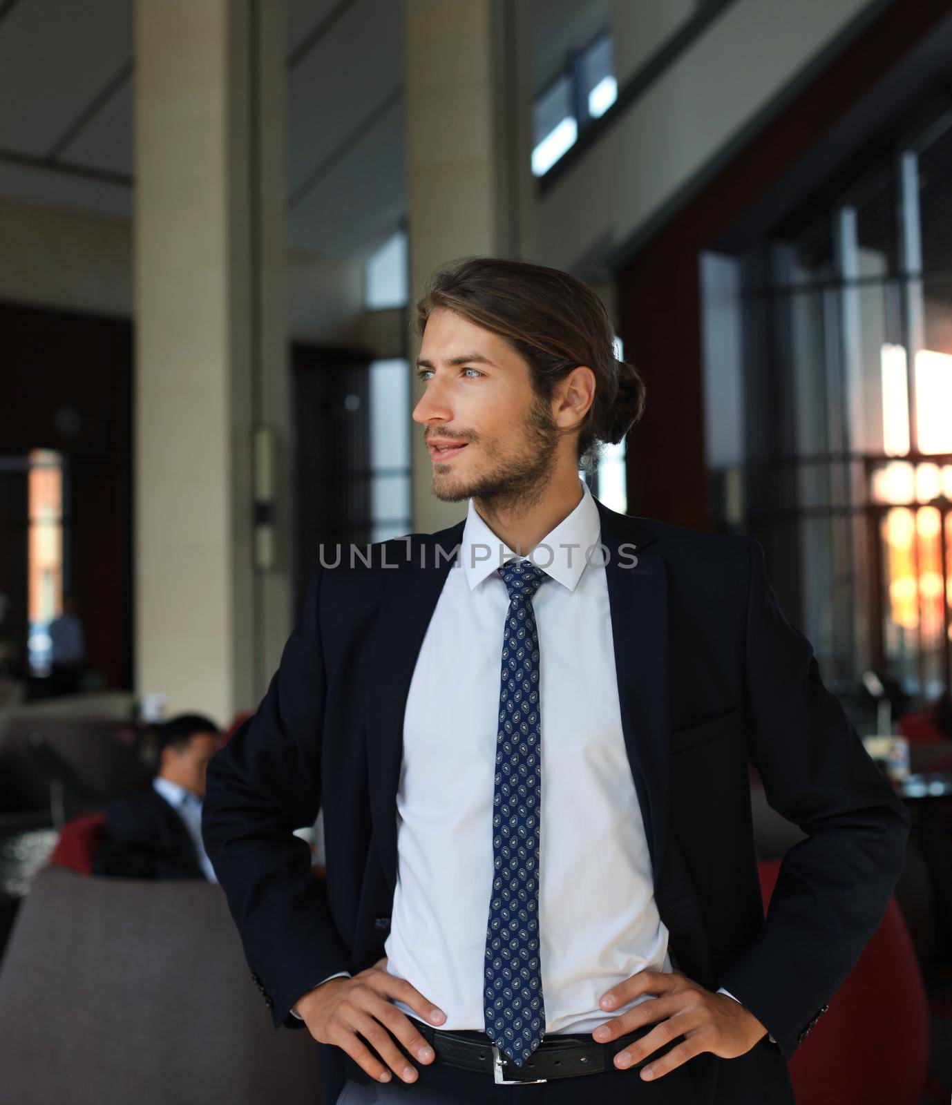 Portrait of happy young businessman standing in hotel lobby.