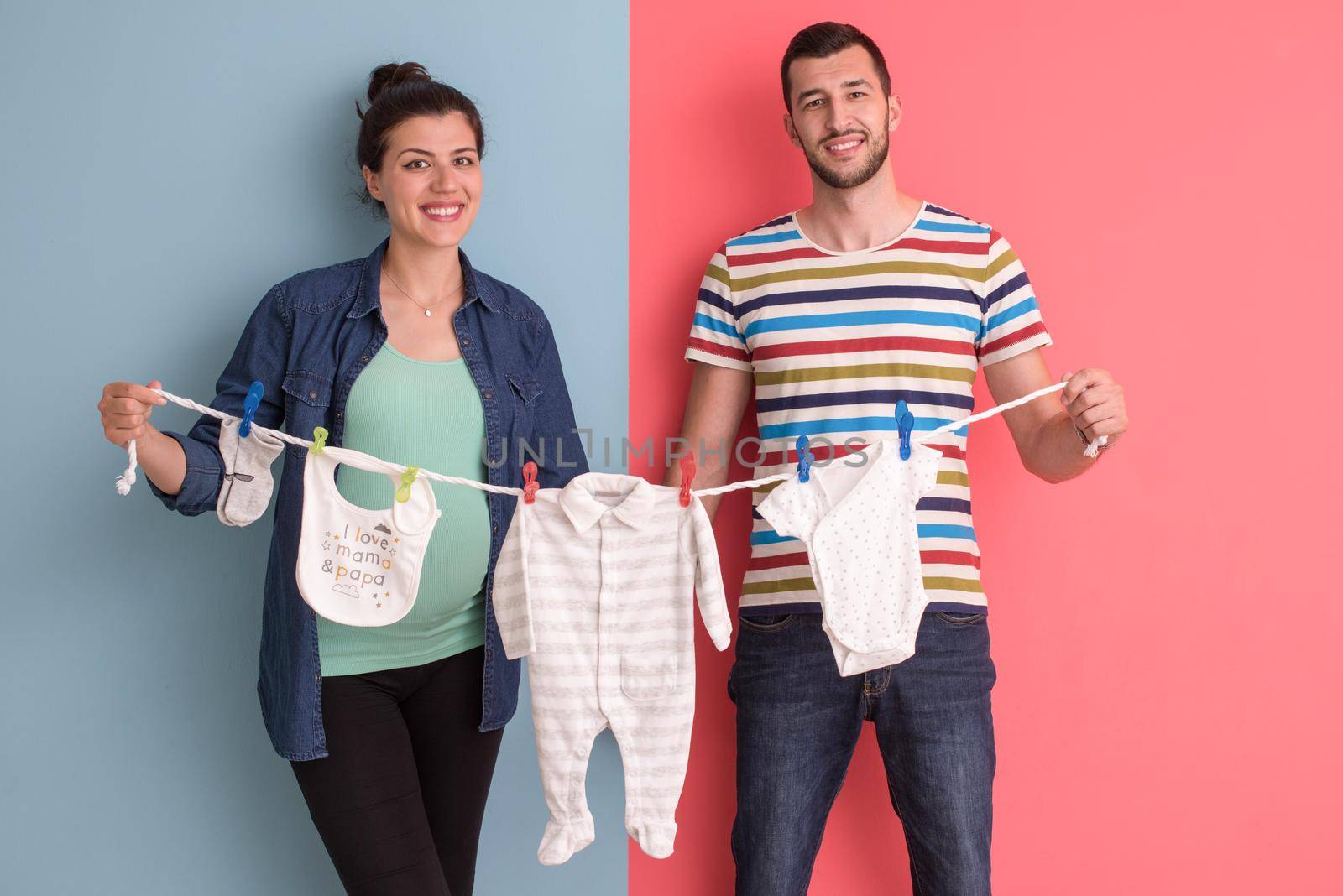 young couple holding baby bodysuits by dotshock