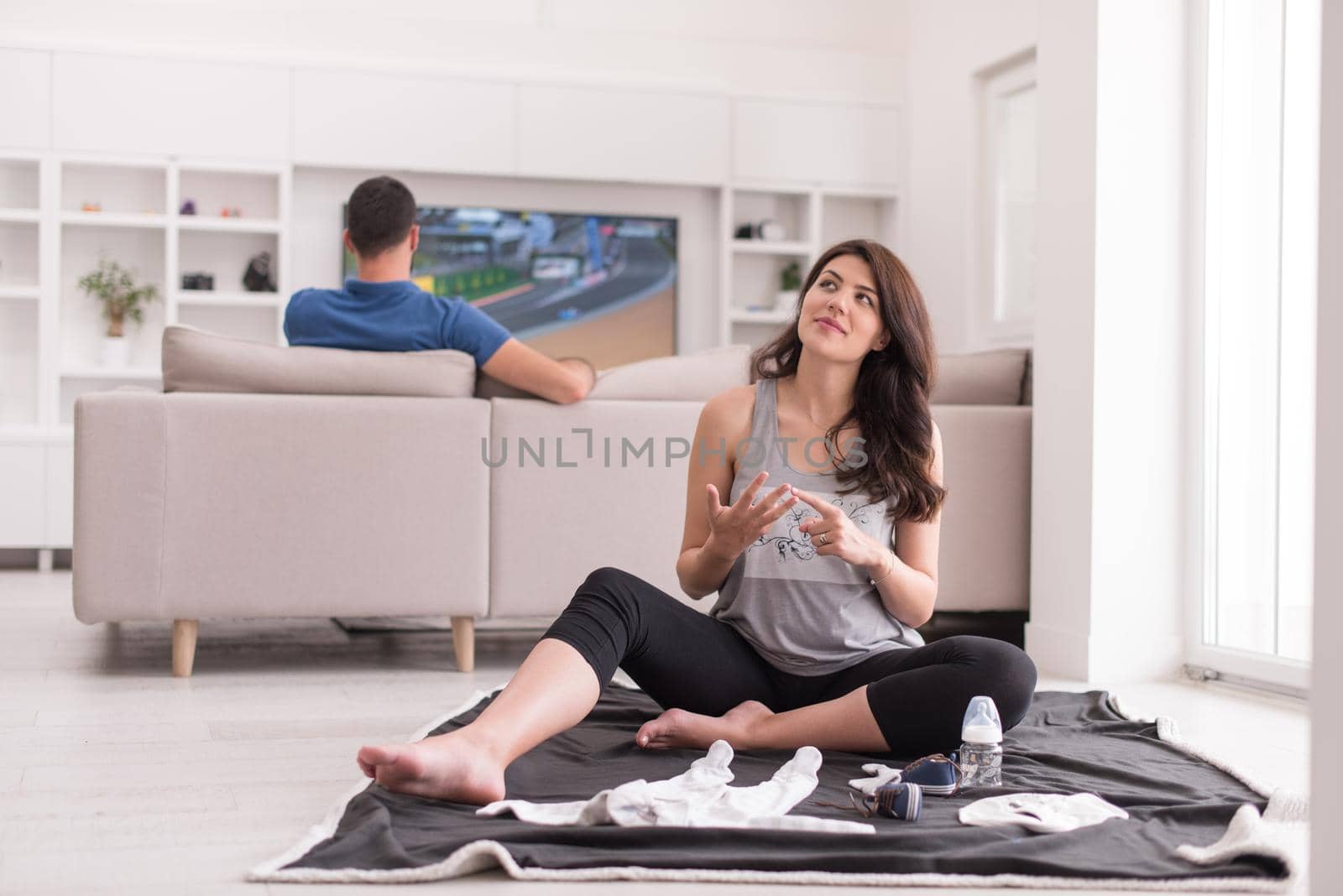 a happy pregnant couple checking a list of things for their unborn baby at home on the floor