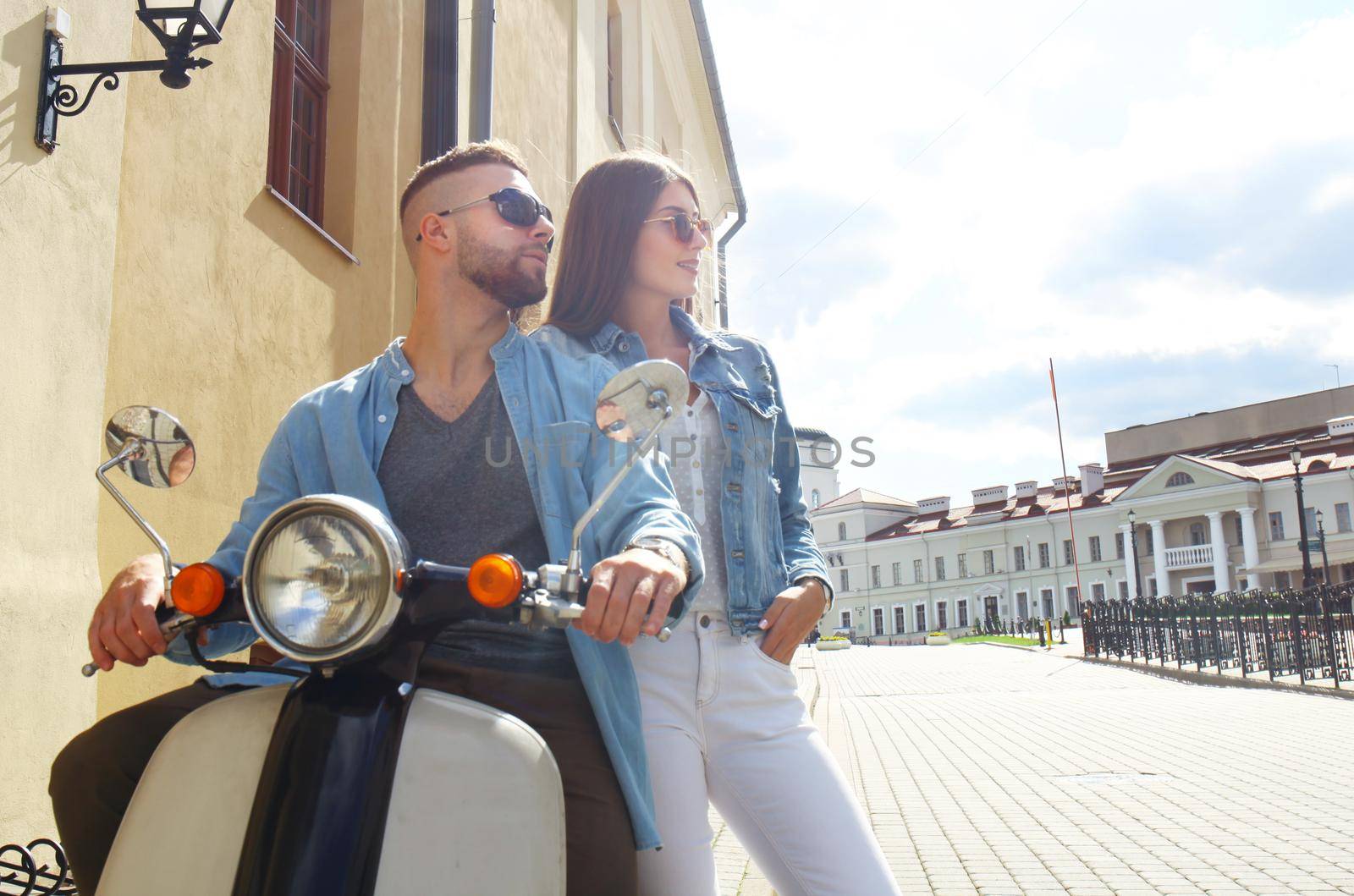 happy young couple riding scooter in town. Handsome guy and young woman travel. Adventure and vacations concept.
