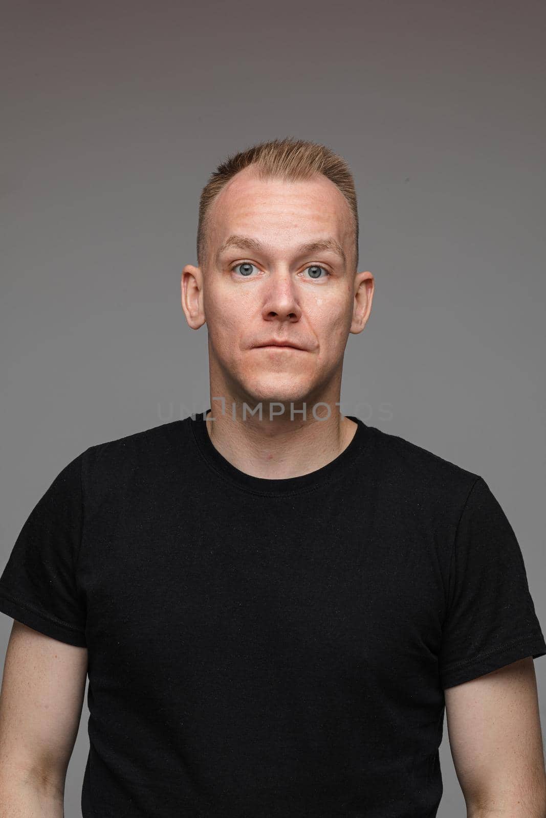 adult caucasian man in black t-shirt and short hair looks to the camera and smiles