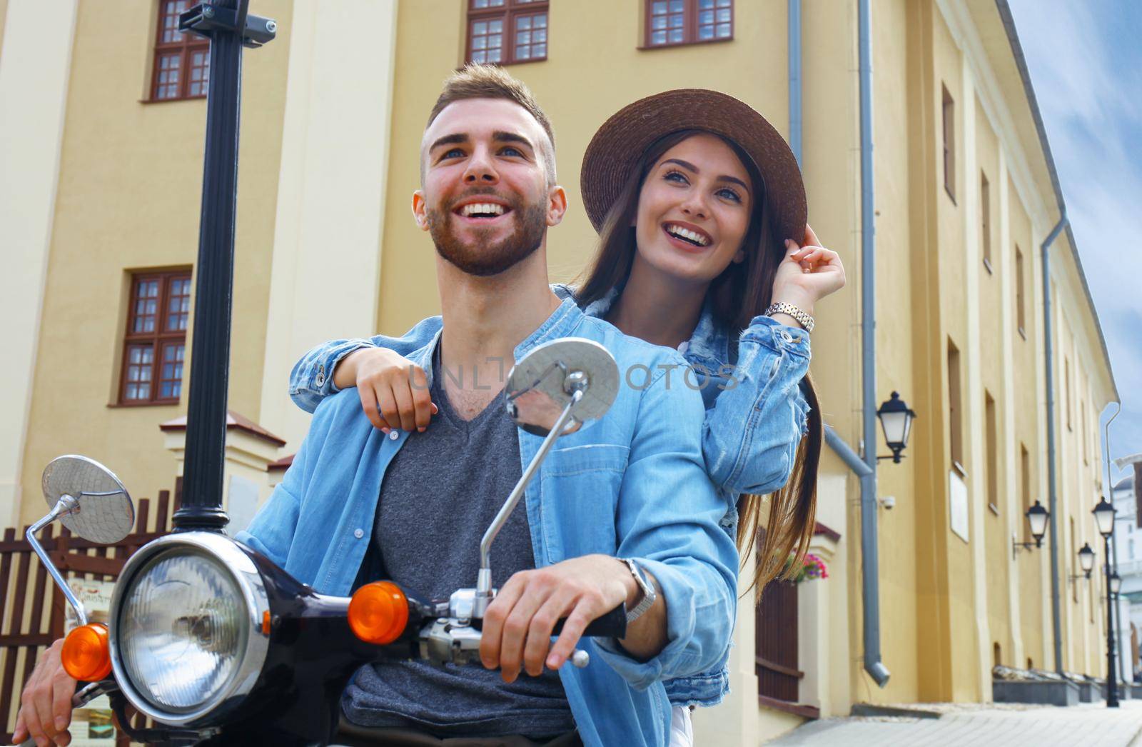 happy young couple riding scooter in town. Handsome guy and young woman travel. Adventure and vacations concept. by tsyhun