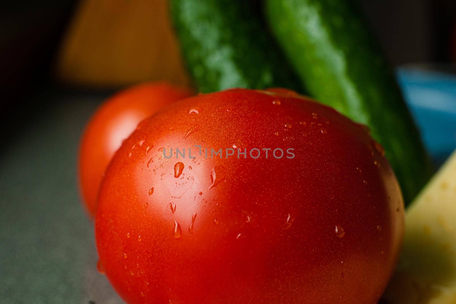 Picture with focus on washed red tomato lies on the table with drops of water on it
