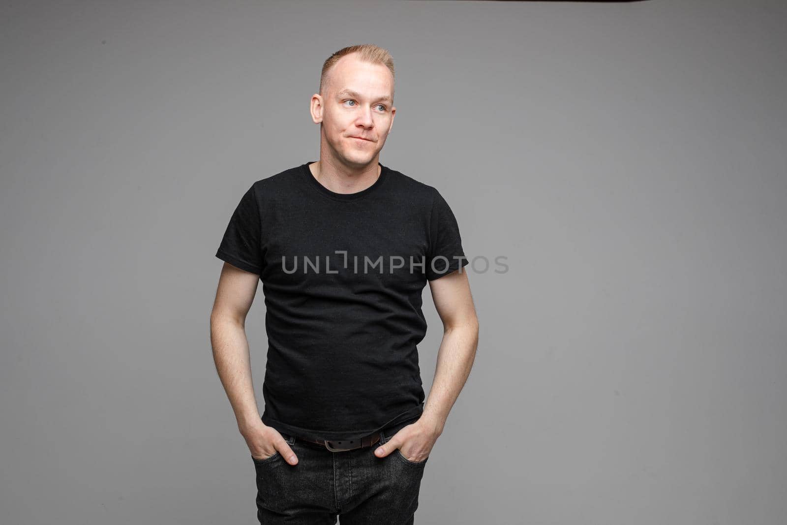 Waist-up photo of indifferent young man in black shirt posing at a professional studio