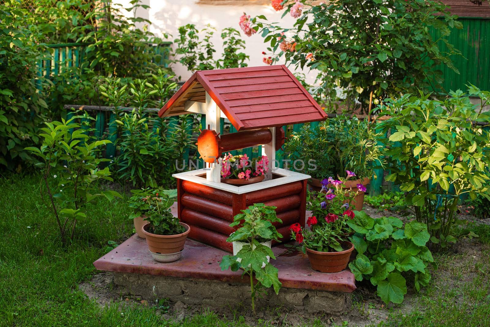 A small decorative well with a lot of color near it in the village yard by StudioLucky