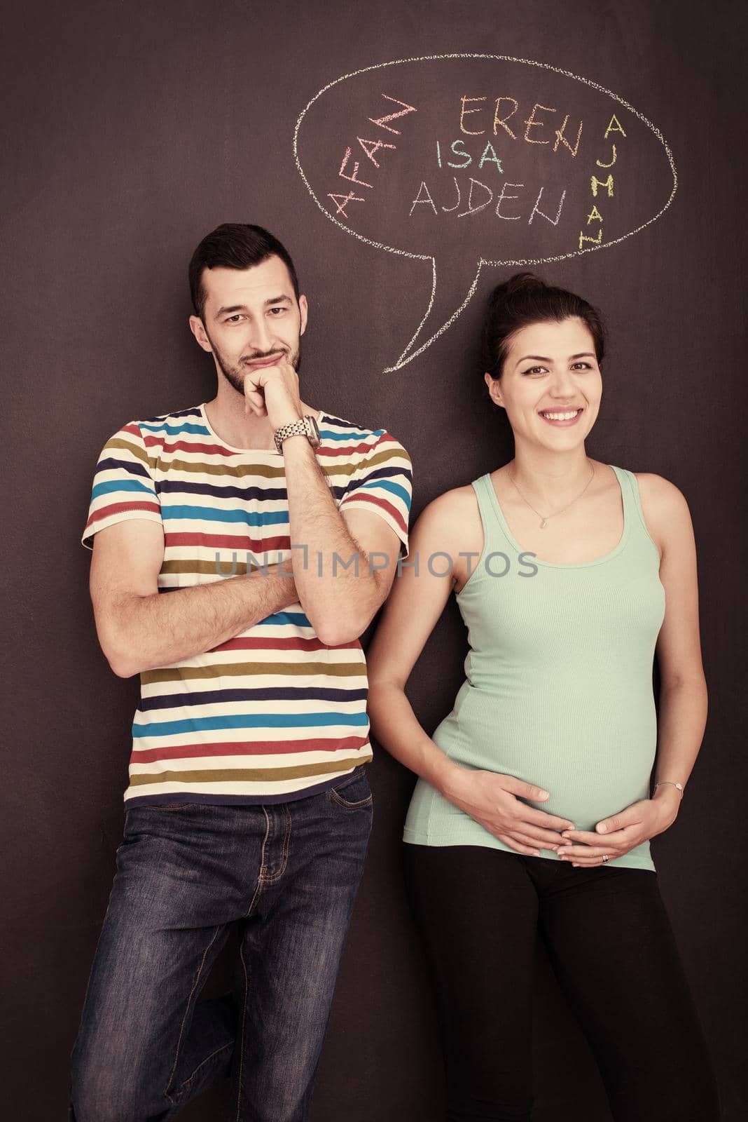 pregnant couple writing on a black chalkboard by dotshock