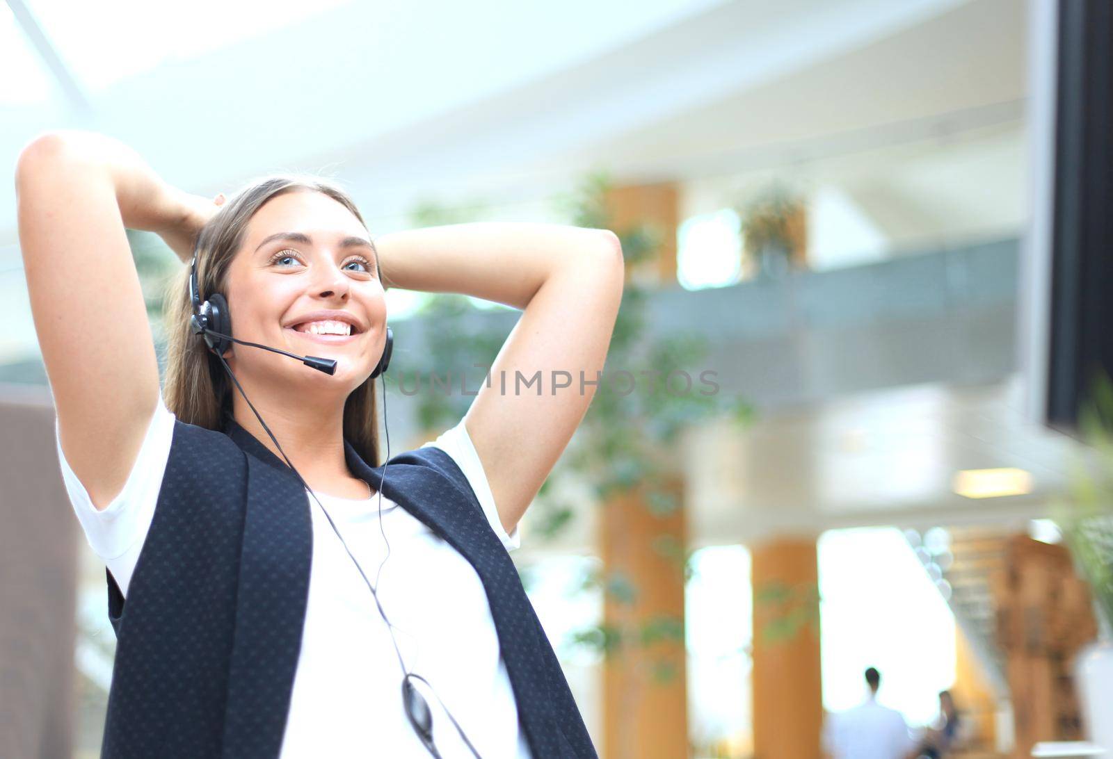 Call center operator in headset resting at workplace in office.