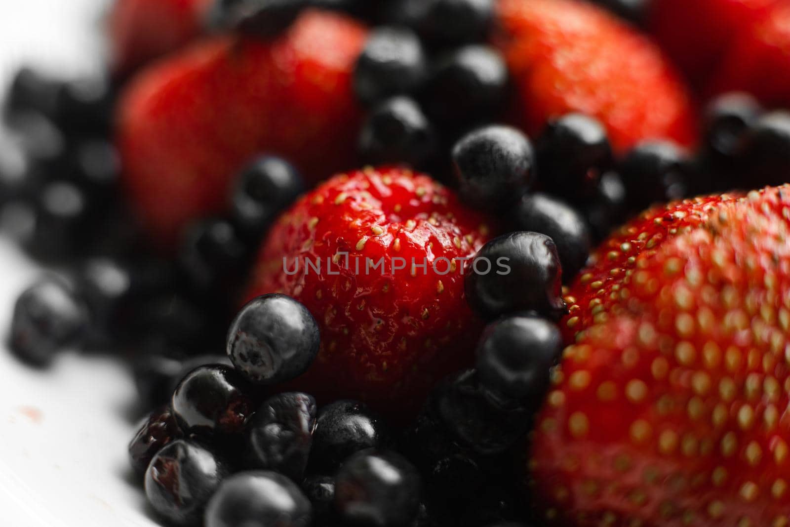 Many juicy fresh ripe red strawberry berries with blackberries isolated on white background by StudioLucky