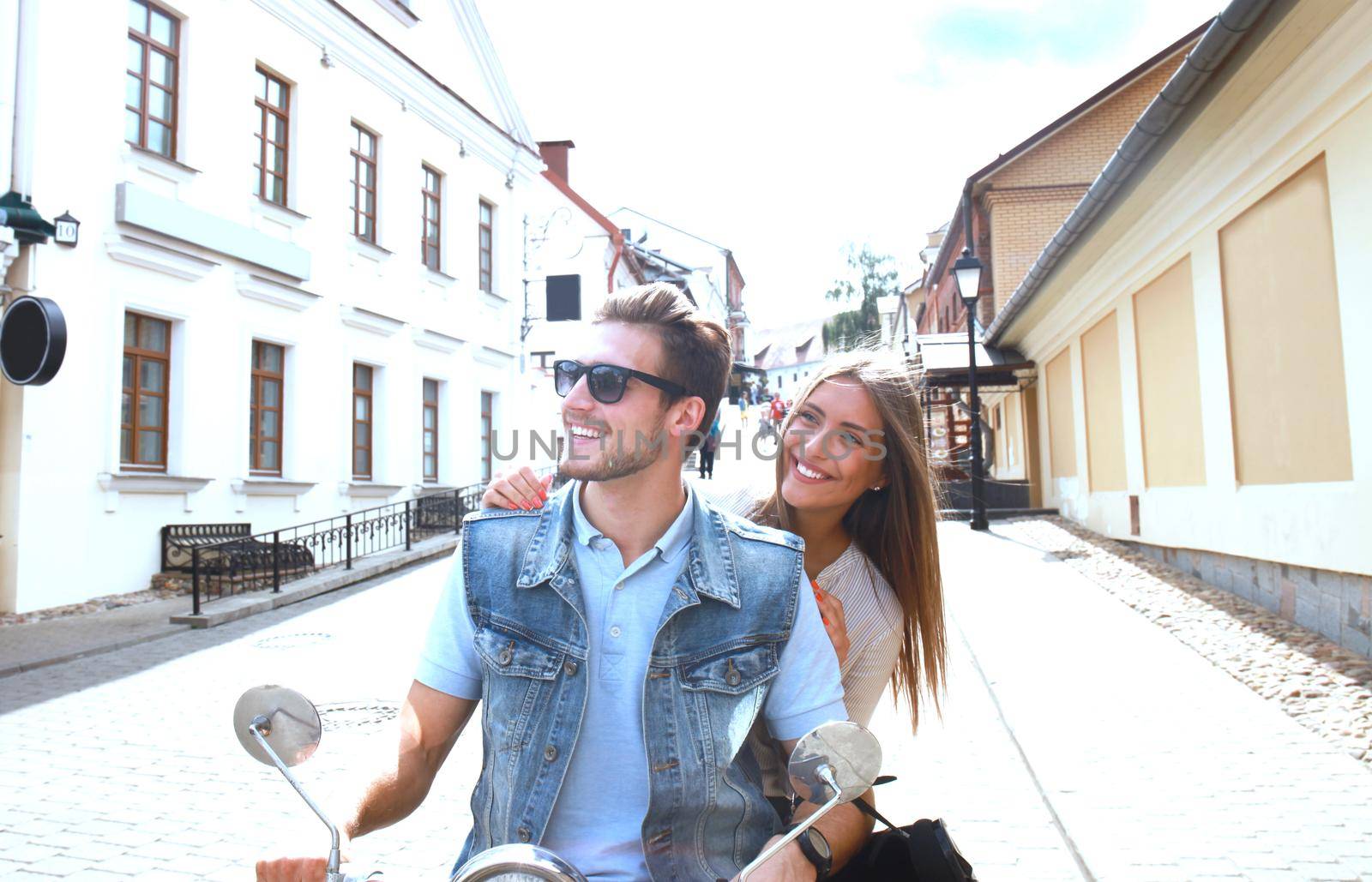 happy young couple riding scooter in town. Handsome guy and young woman travel. Adventure and vacations concept. by tsyhun