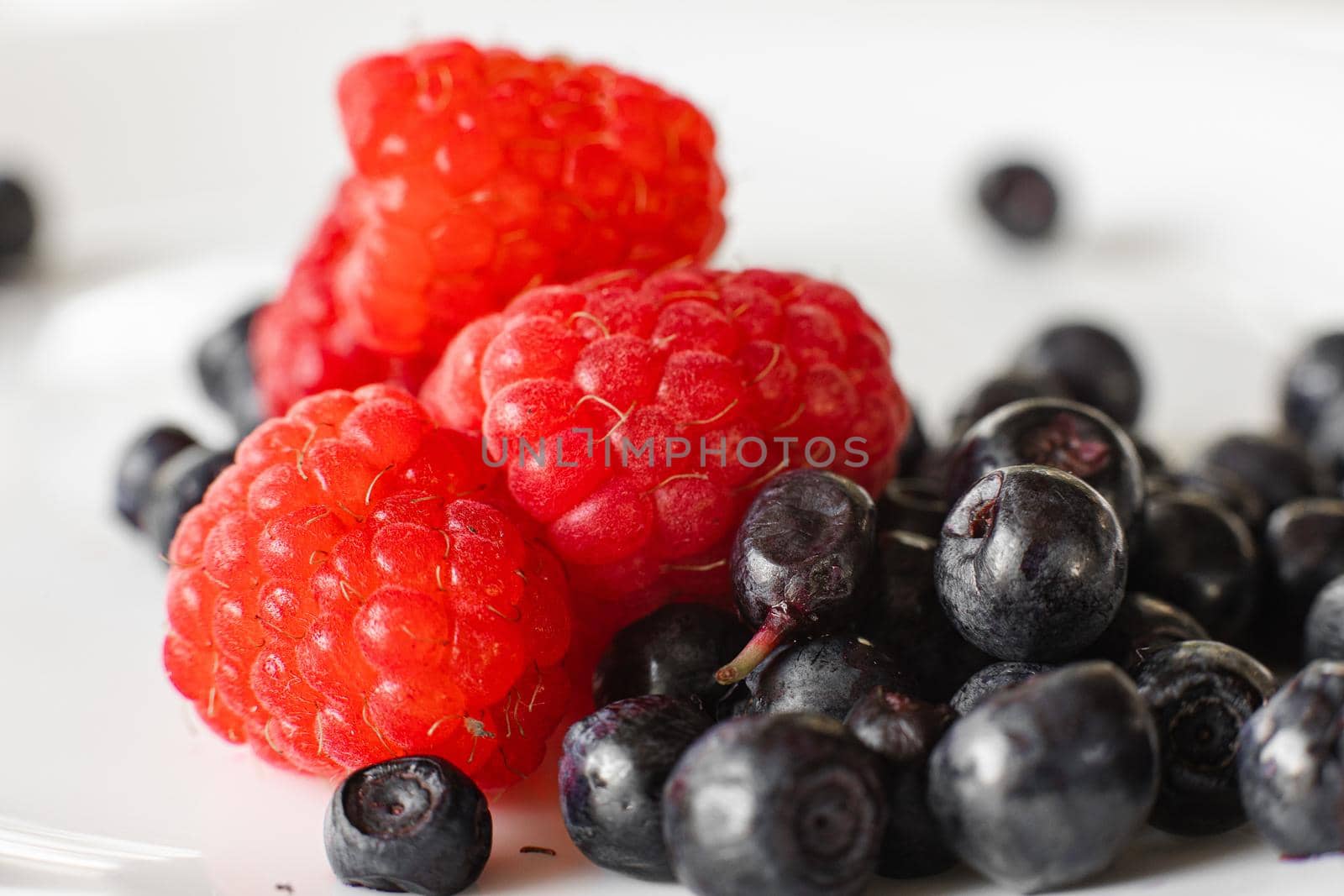 Many juicy fresh ripe red raspberry berries with blackberries isolated on white background by StudioLucky