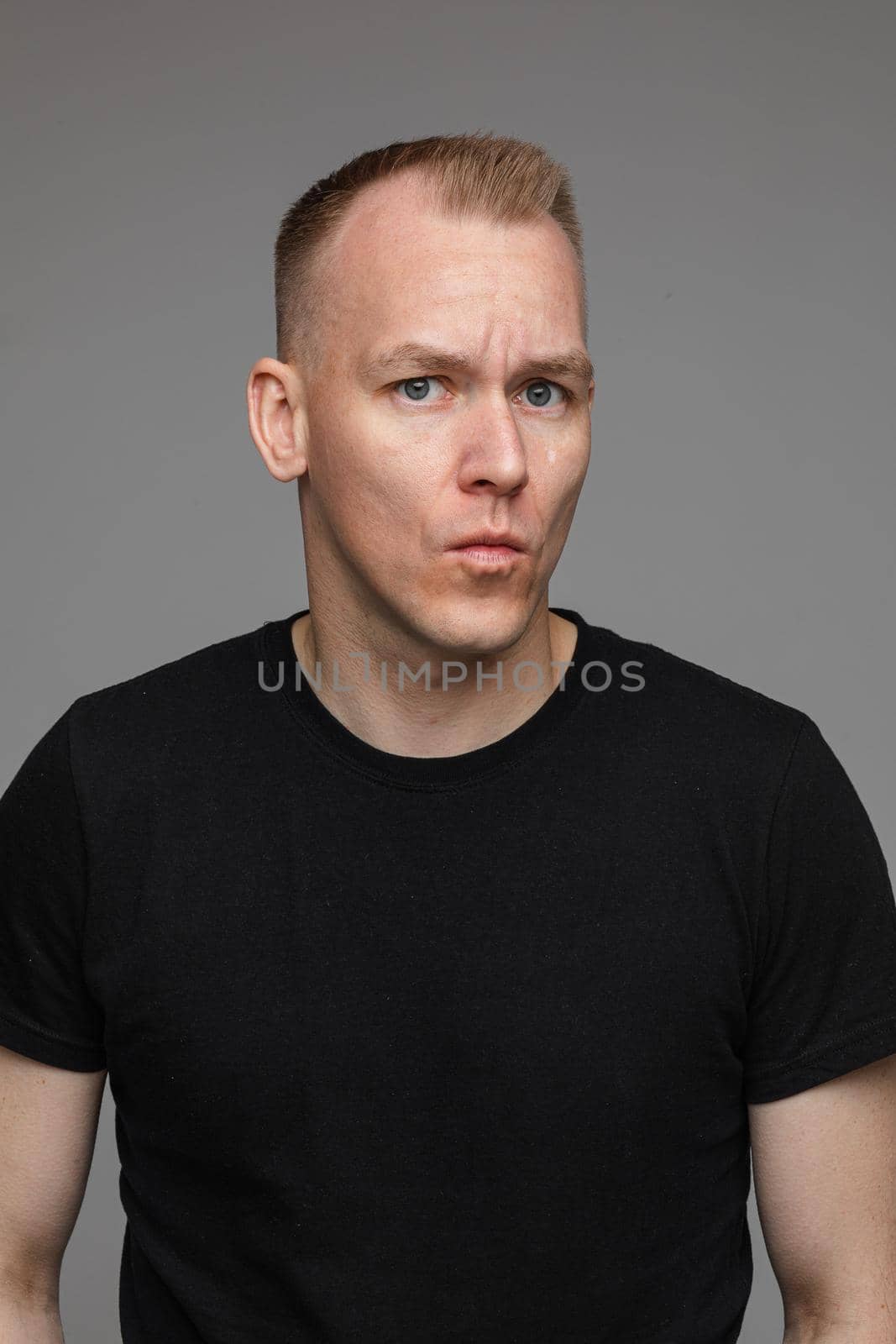 adult caucasian man in black t-shirt and short hair looks aside and thinks