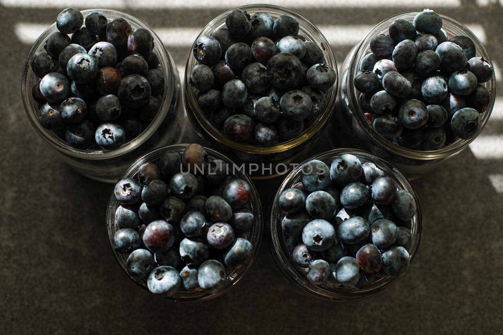 Many large beautiful juicy fresh blueberries lie in glass jars.