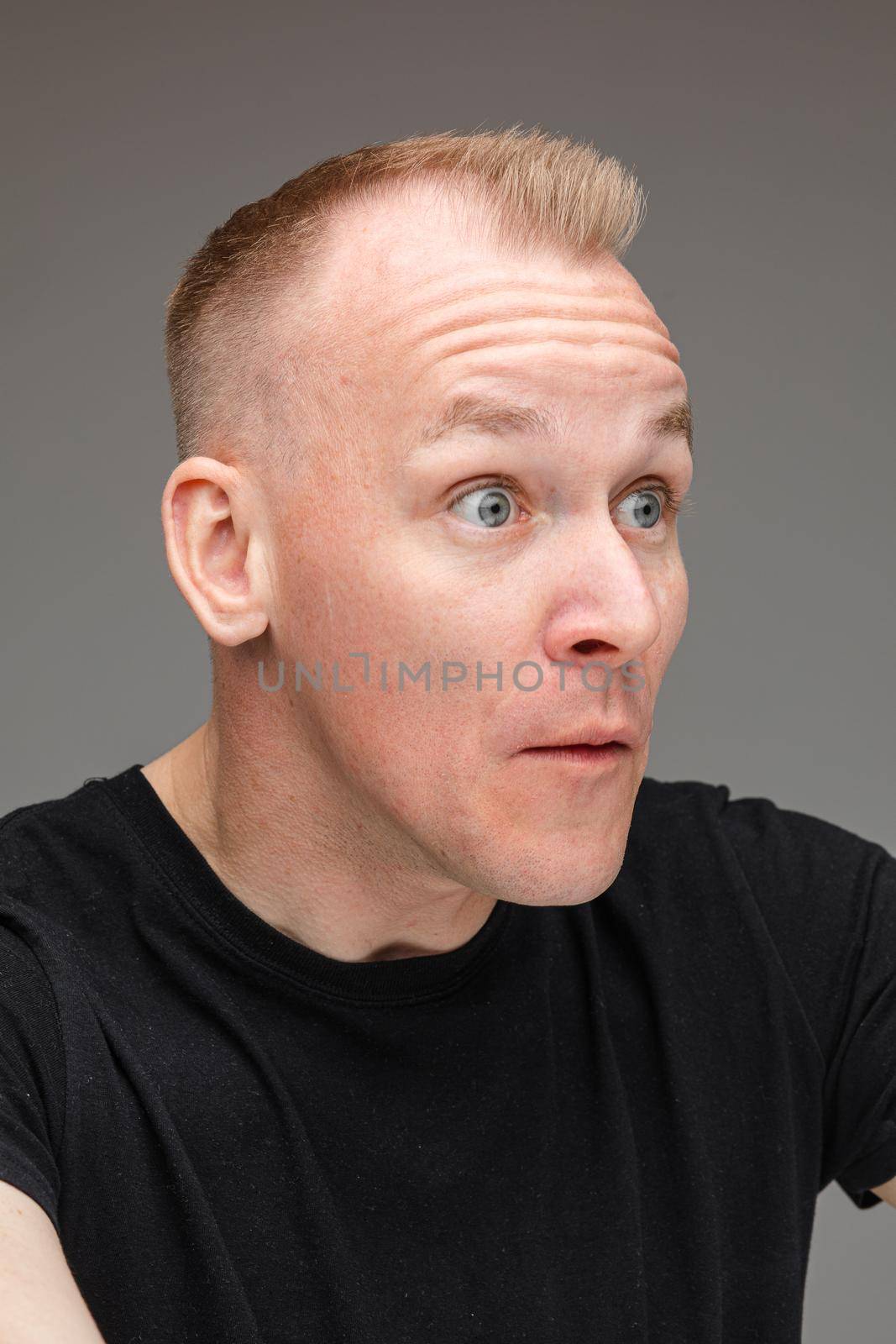 Close-up photo of fair-haired Caucasian man opening eyes wide and looking to the side
