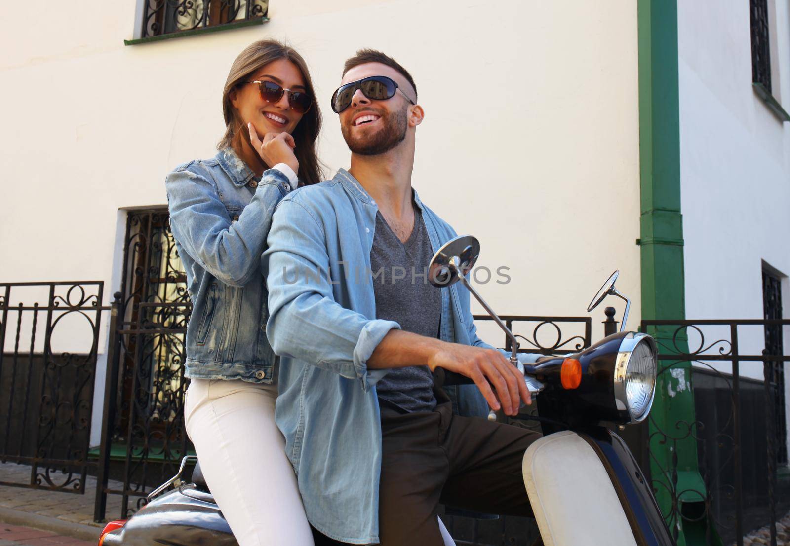 happy young couple riding scooter in town. Handsome guy and young woman travel. Adventure and vacations concept.