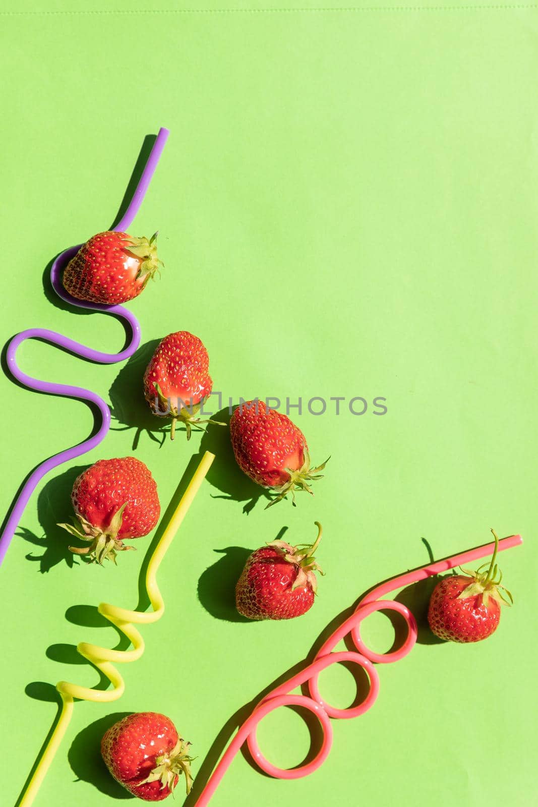 Creative layout strawberry lemonade ingredients.cocktail straws on green background. Summer drinks. Minimal food concept. Party, holidays card.