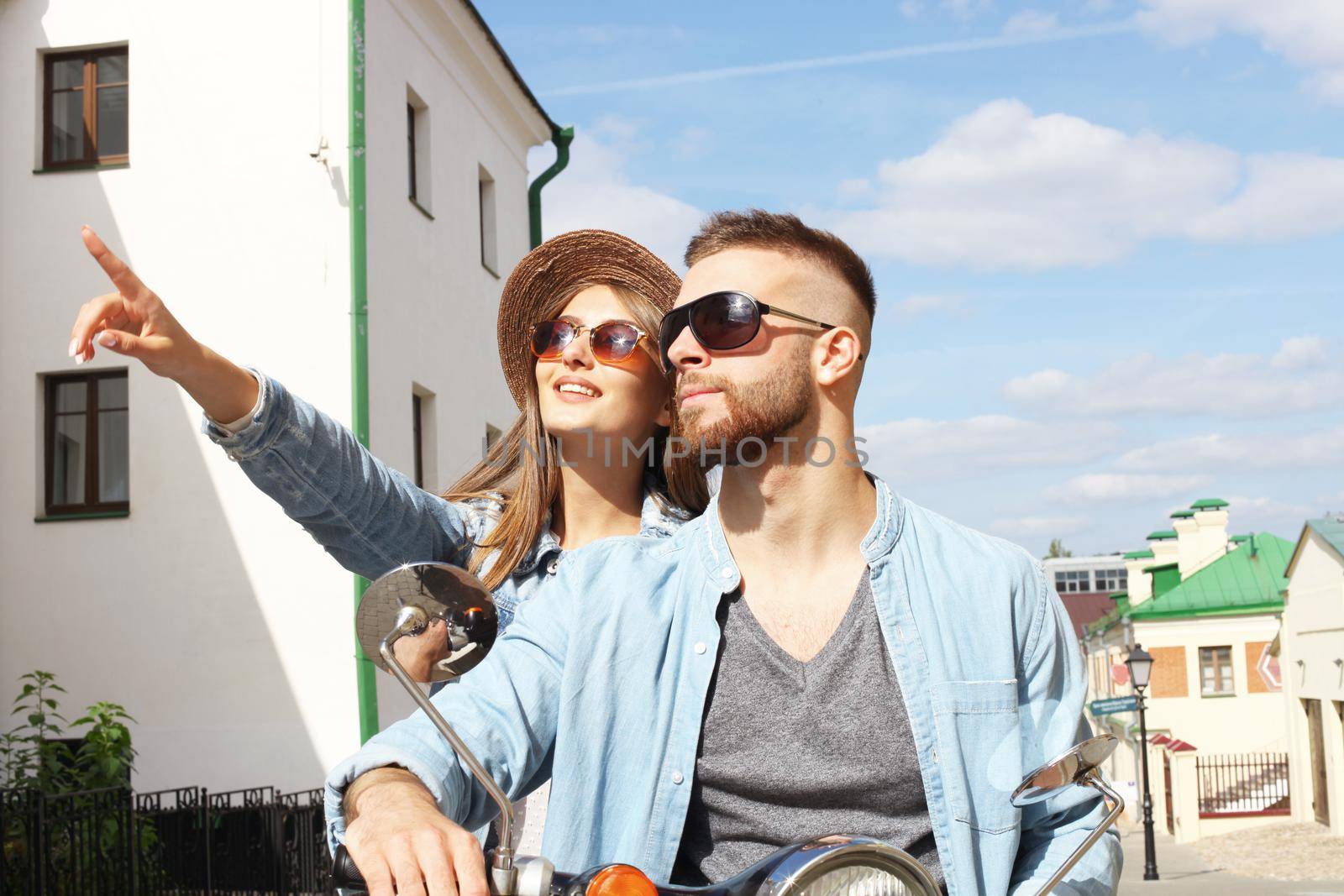 happy young couple riding scooter in town. Handsome guy and young woman travel. Adventure and vacations concept.