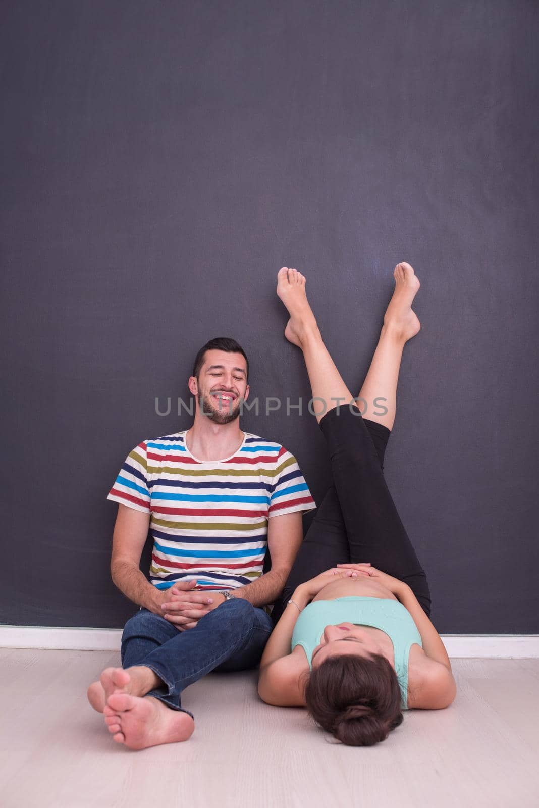 happy pregnant couple relaxing in front of black chalkboard on the floor at home
