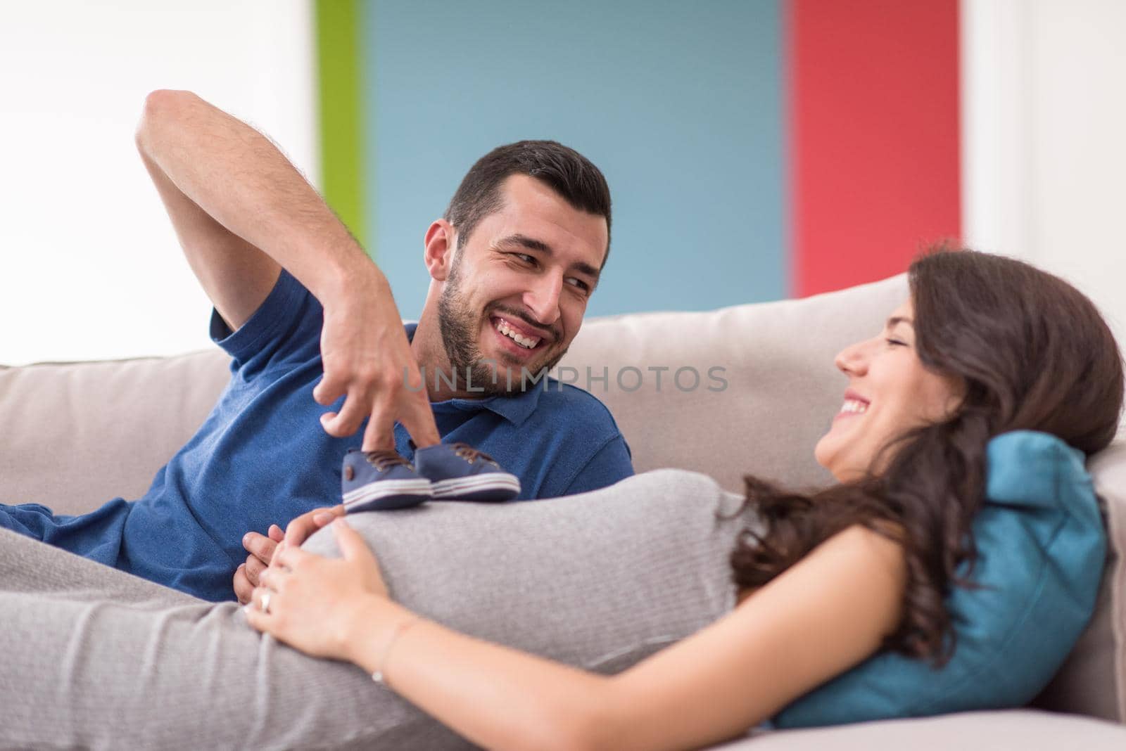 happy pregnant couple relaxing on sofa couch at home