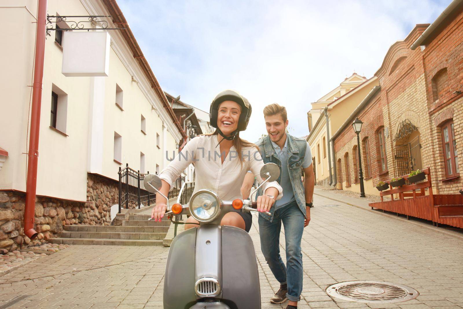 happy young couple riding scooter in town. Handsome guy and young woman travel. Adventure and vacations concept.