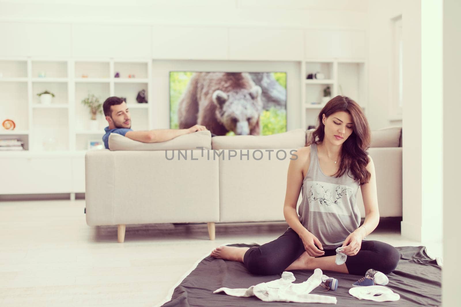 a happy pregnant couple checking a list of things for their unborn baby at home on the floor