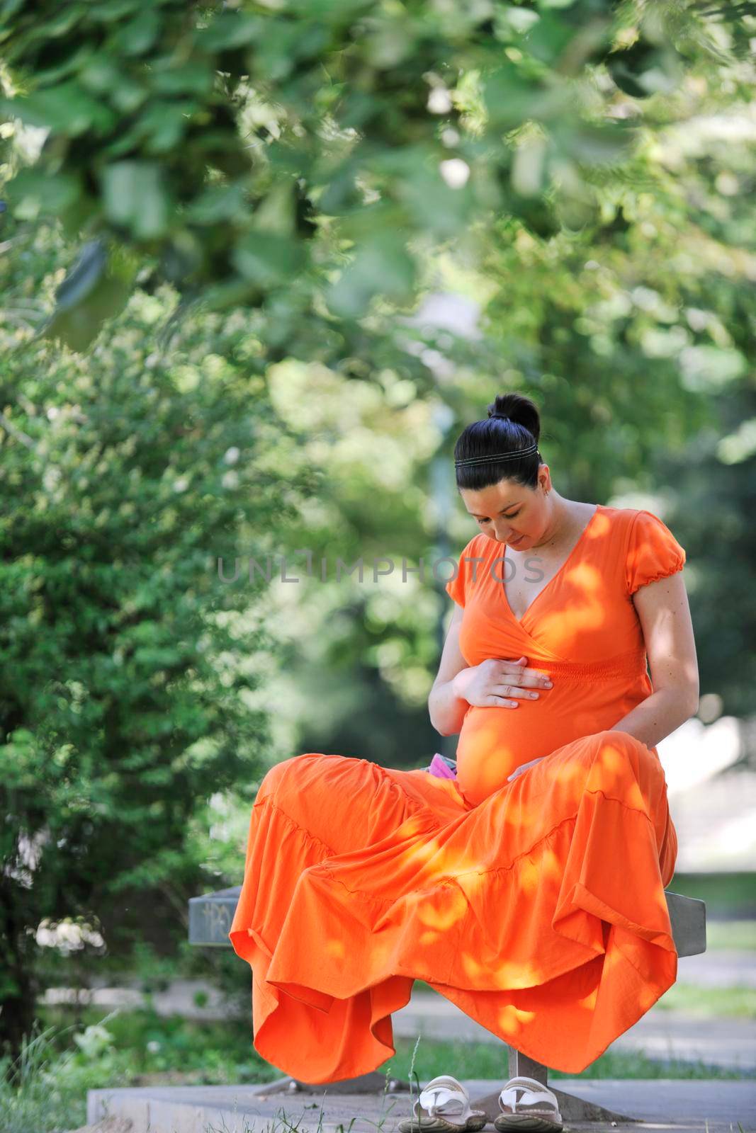 beautiful young happy pregnant woman outdoor in bright nature in orange dress