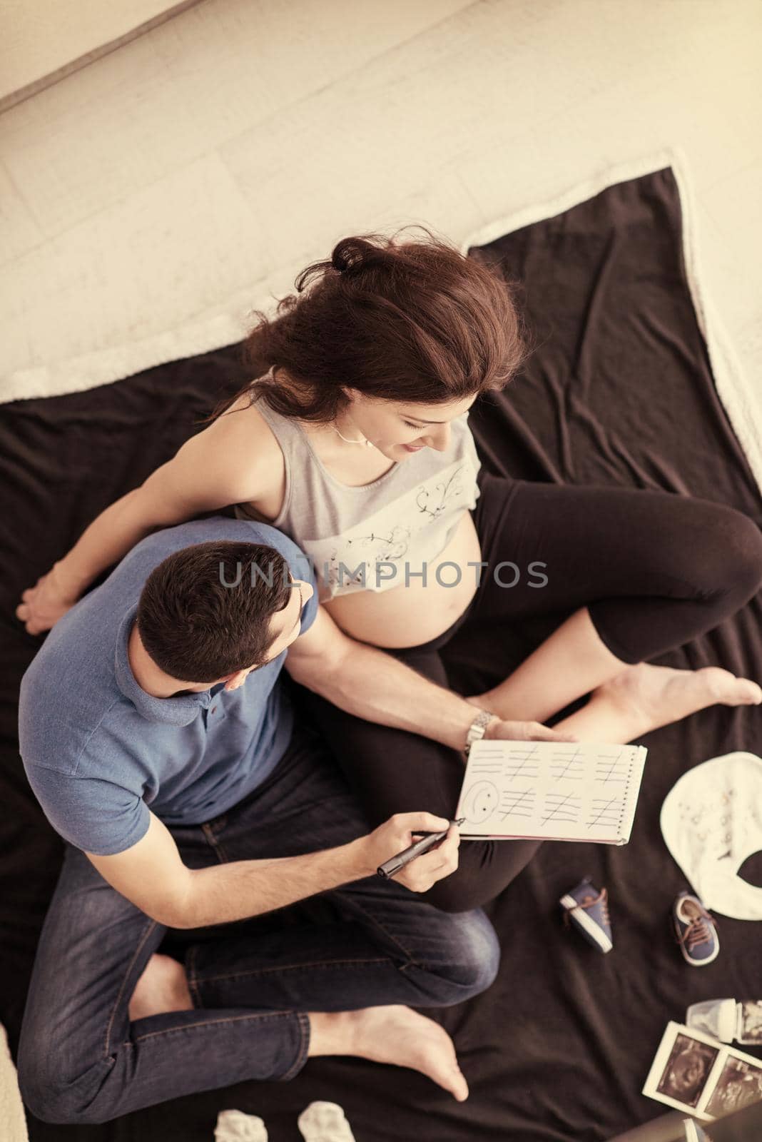 top view of a happy pregnant couple checking a list of things for their unborn baby at home on the floor